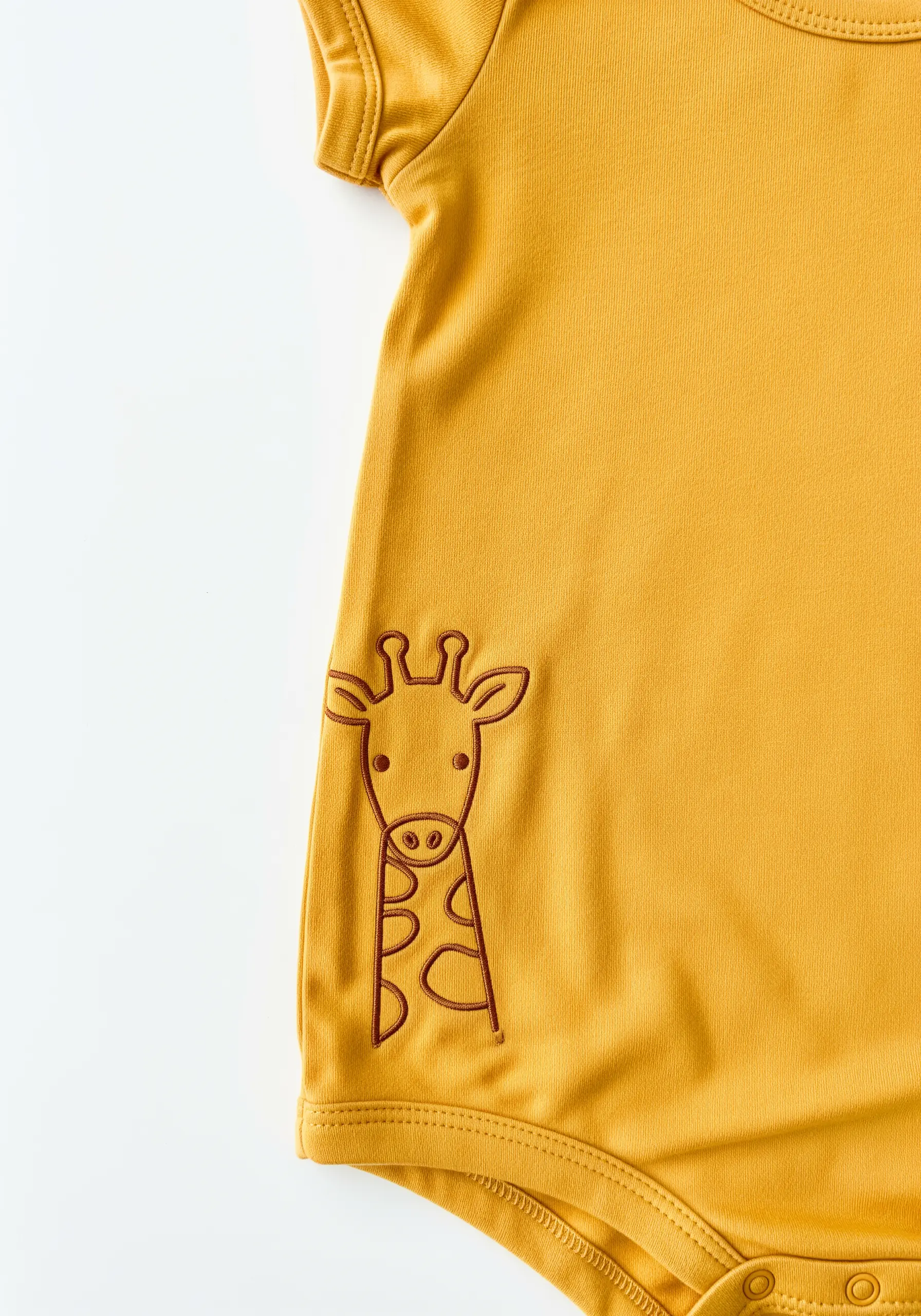 A line-art giraffe motif embroidered asymmetrically on a yellow baby bodysuit.