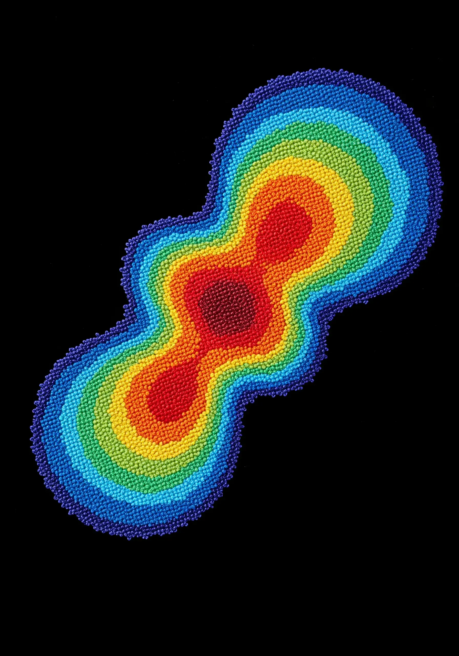 An abstract, organic shape filled with concentric rings of colorful seed beads.