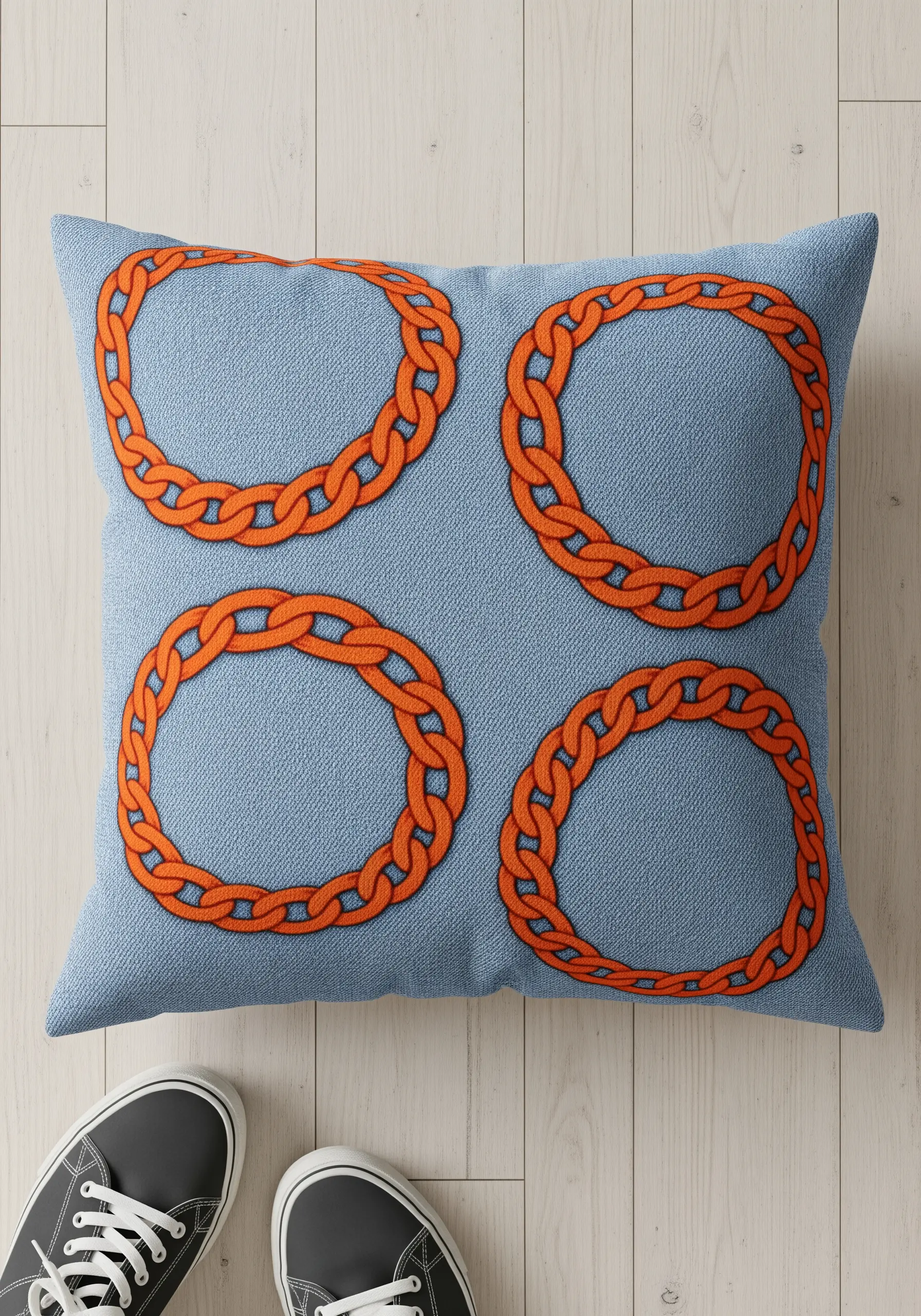 Four repeating orange chain-link circles stitched on a blue denim pillow.