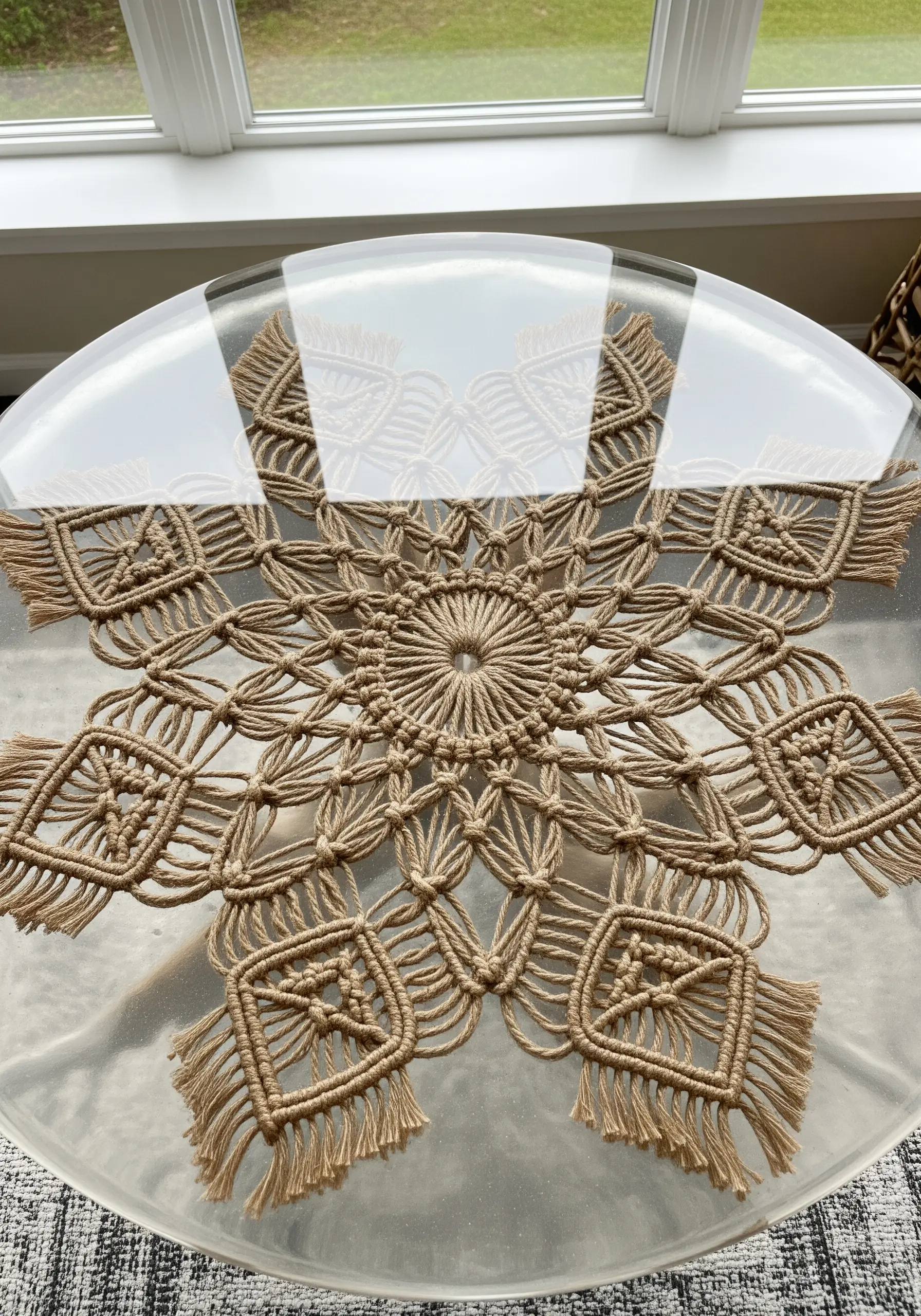 A large macrame doily preserved under the clear resin top of a round table.
