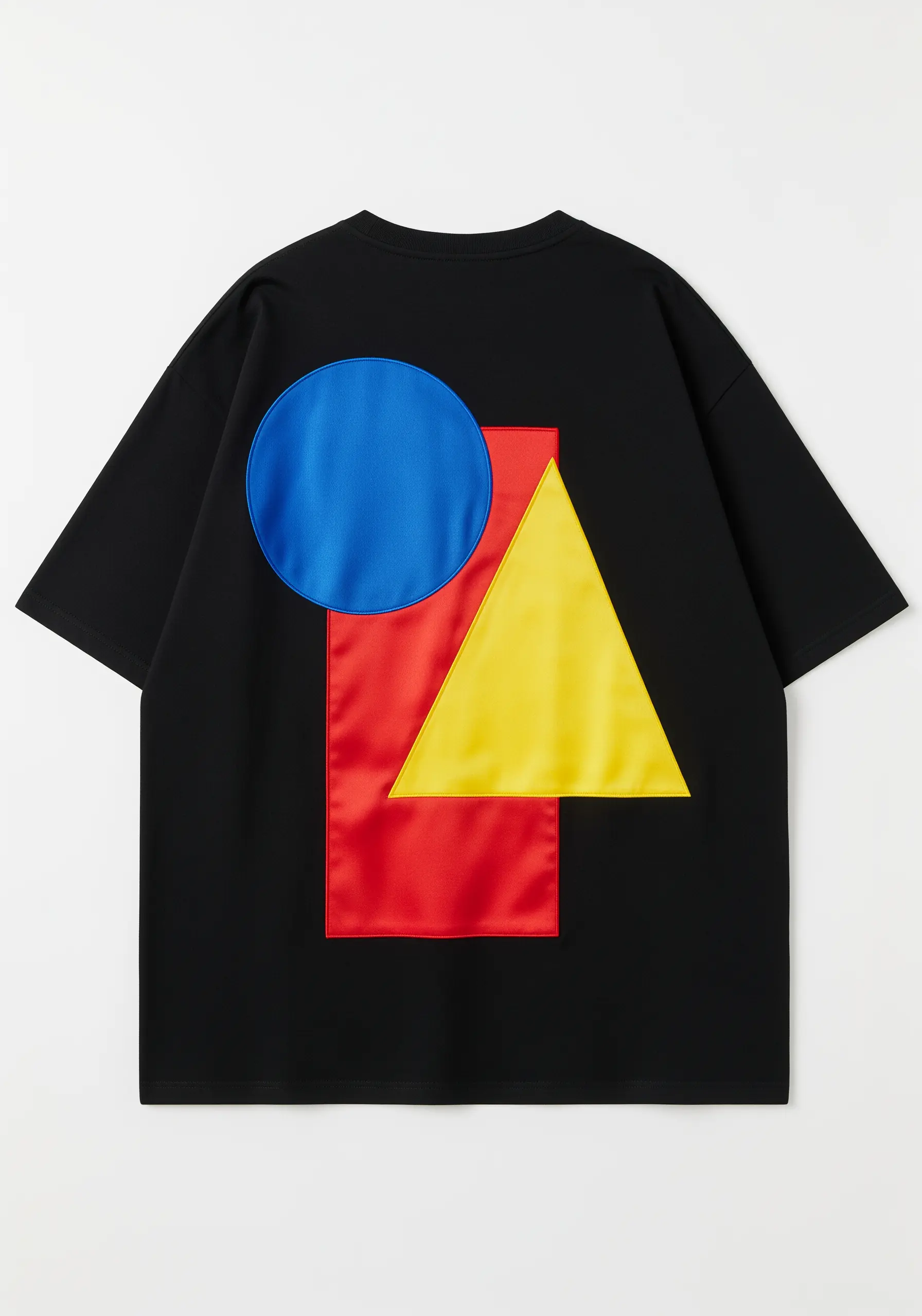 Bold geometric appliqué with a blue circle, red rectangle, and yellow triangle on a black t-shirt.