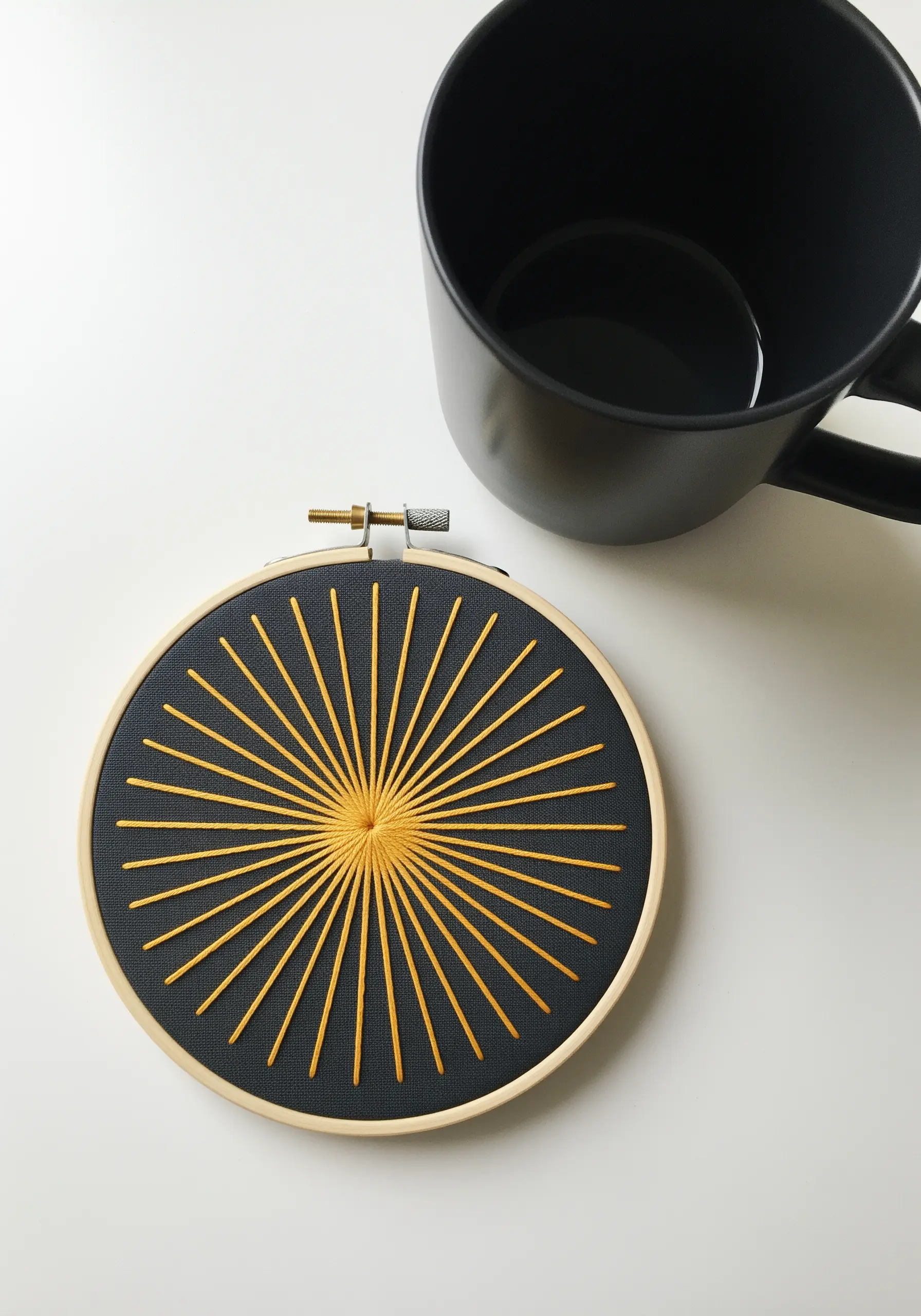A geometric sunburst embroidered with golden-yellow thread on dark gray fabric.