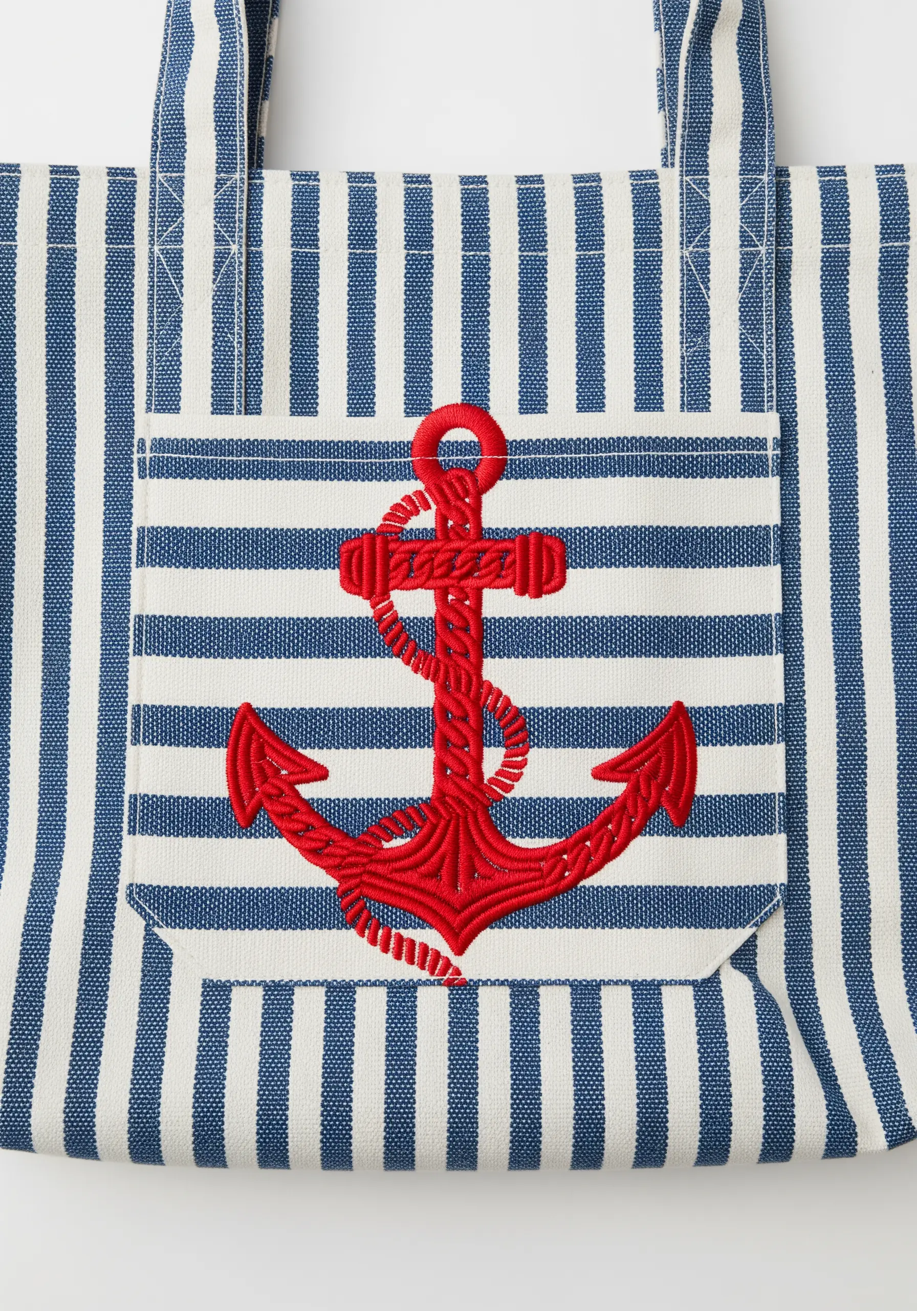 A red, padded satin stitch anchor embroidered on a striped blue and white pocket.