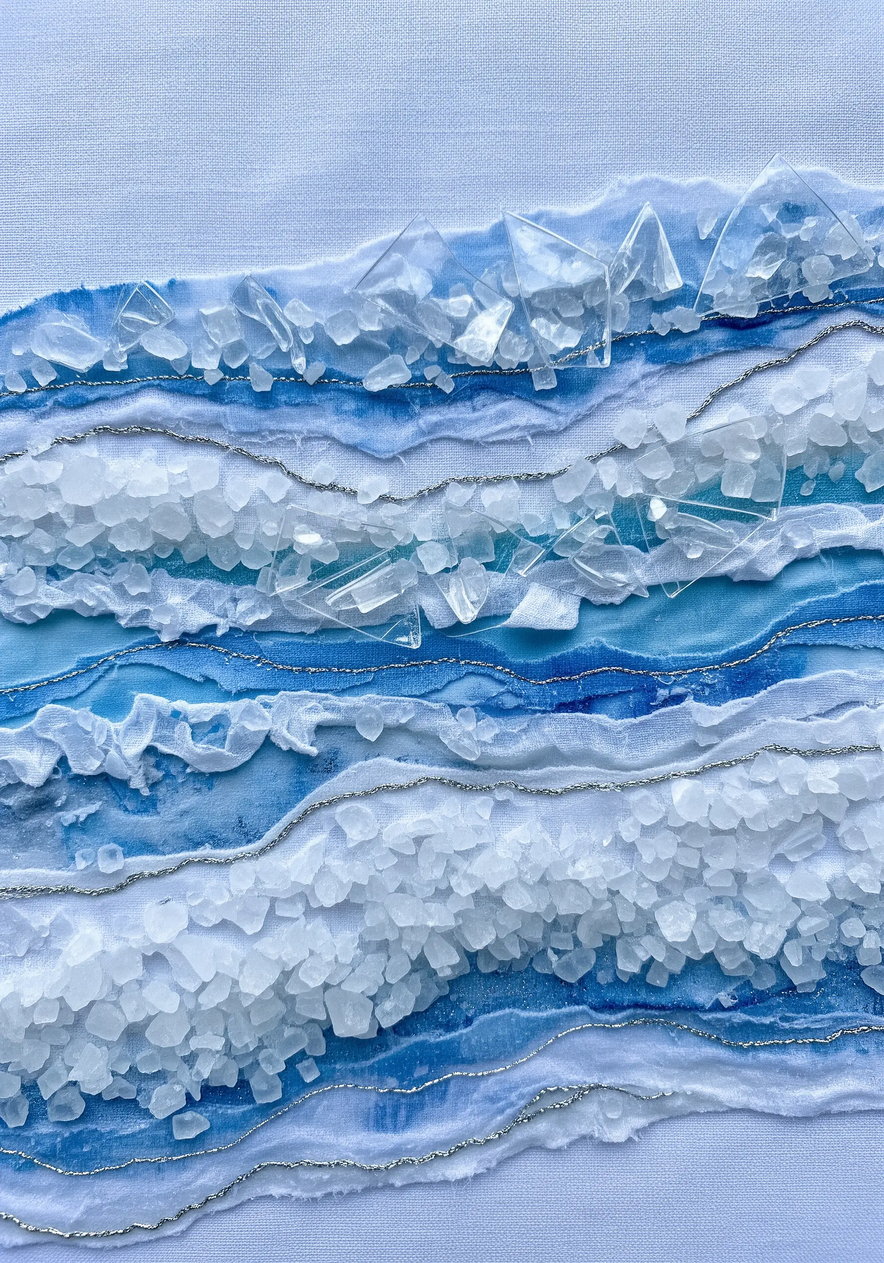 An abstract textile piece of icy water with layered fabrics, silver thread, and salt crystals.