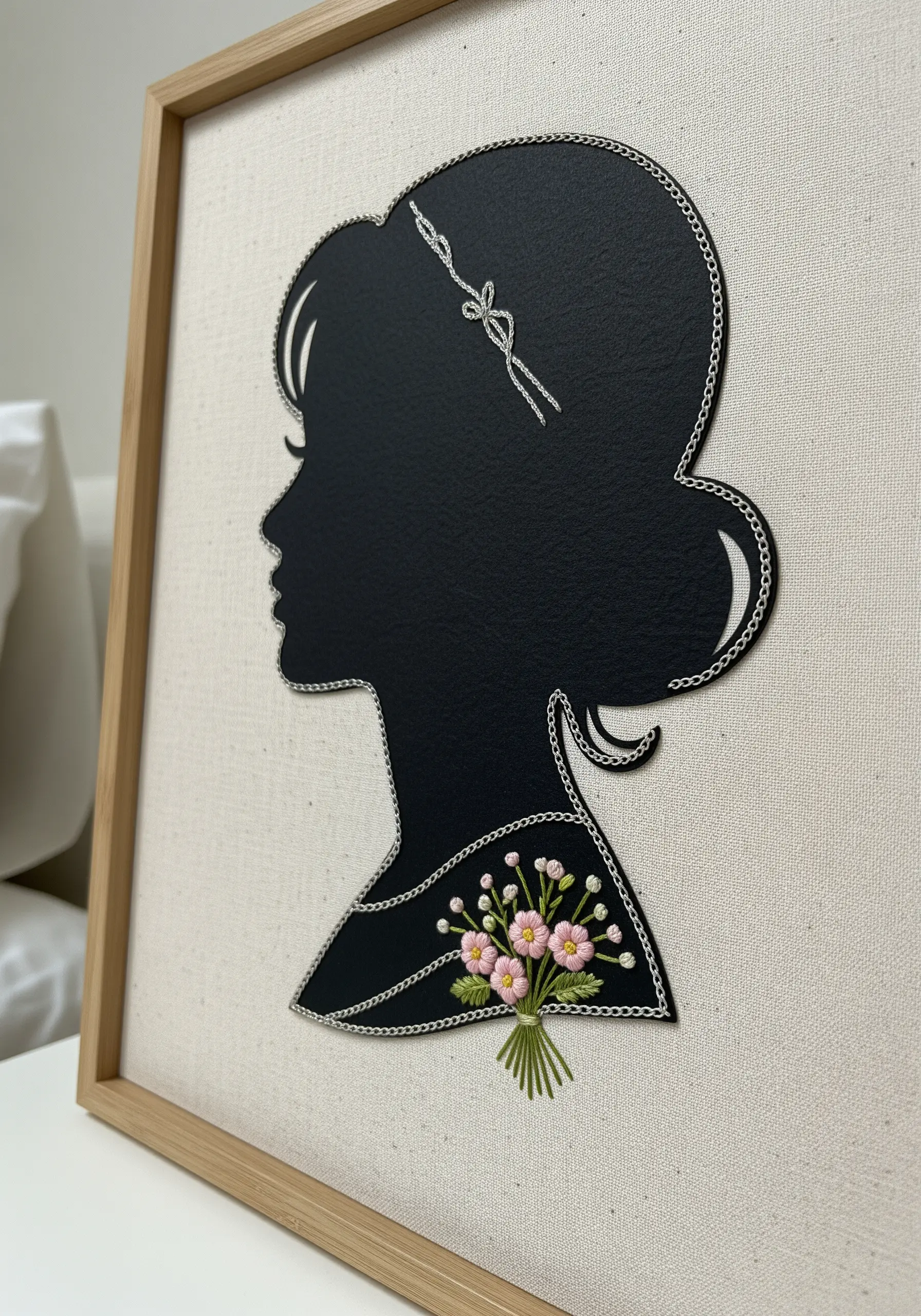 A black paper silhouette outlined in silver chain stitch with a tiny embroidered floral bouquet.