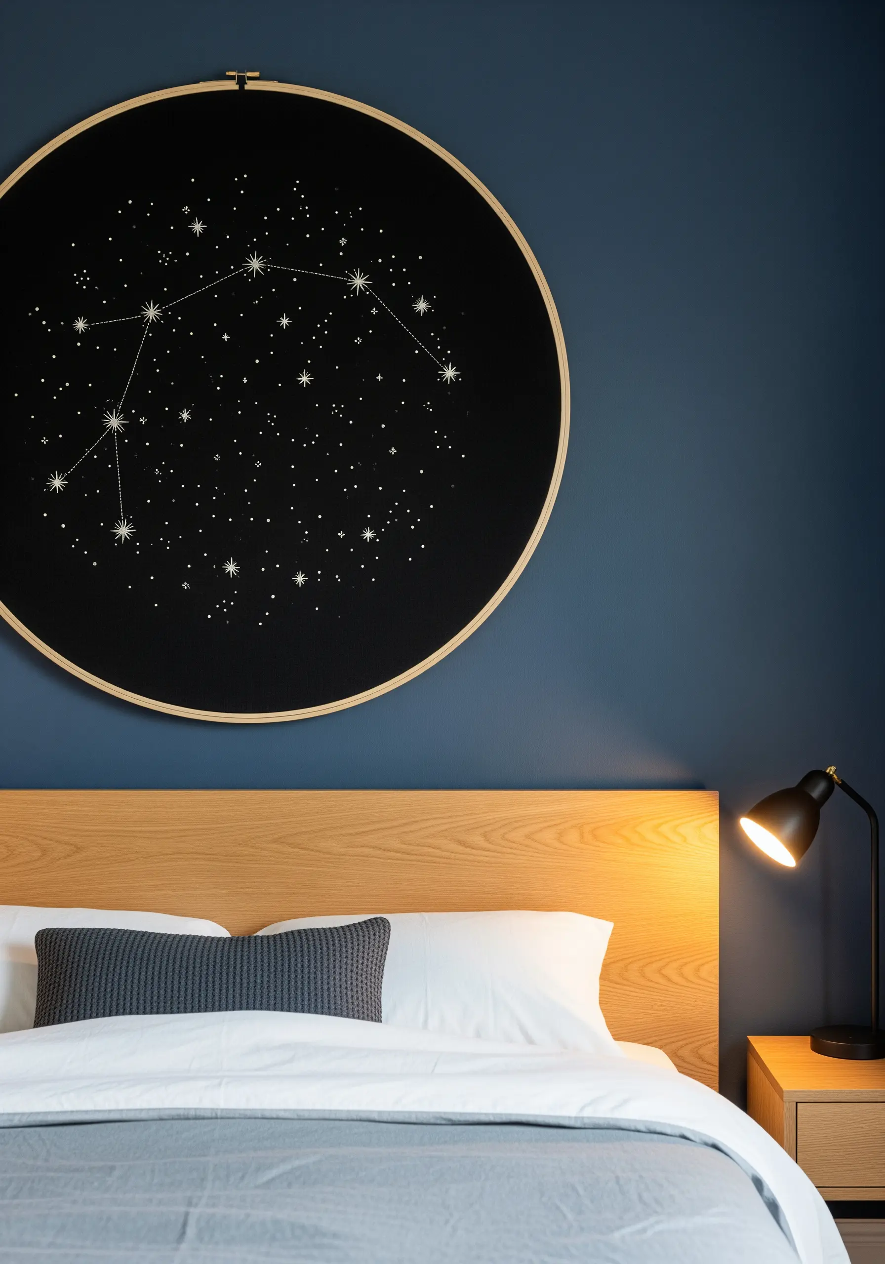 Large-scale constellation embroidery in a hoop above a modern bed.