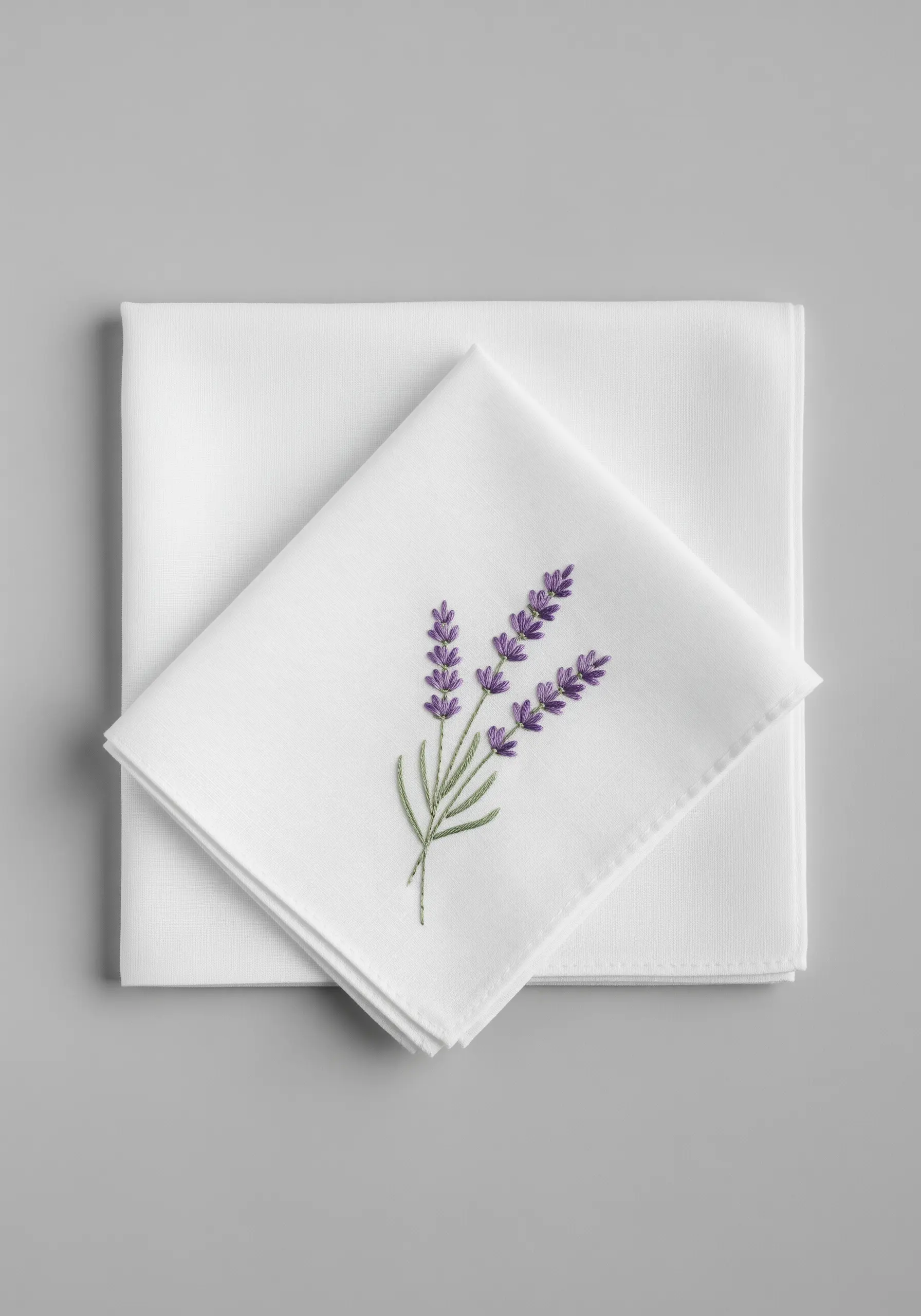 Detailed embroidery of three lavender sprigs with purple blossoms on a white cotton handkerchief.