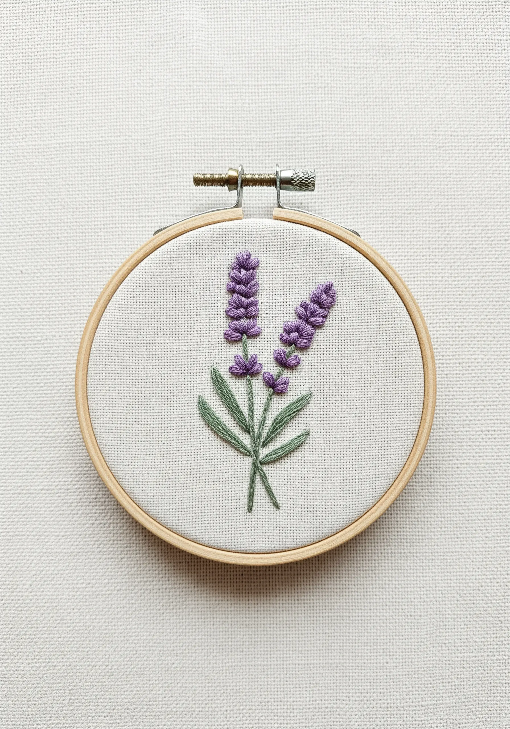 Two lavender sprigs embroidered with purple French knots and green fishbone stitch leaves.