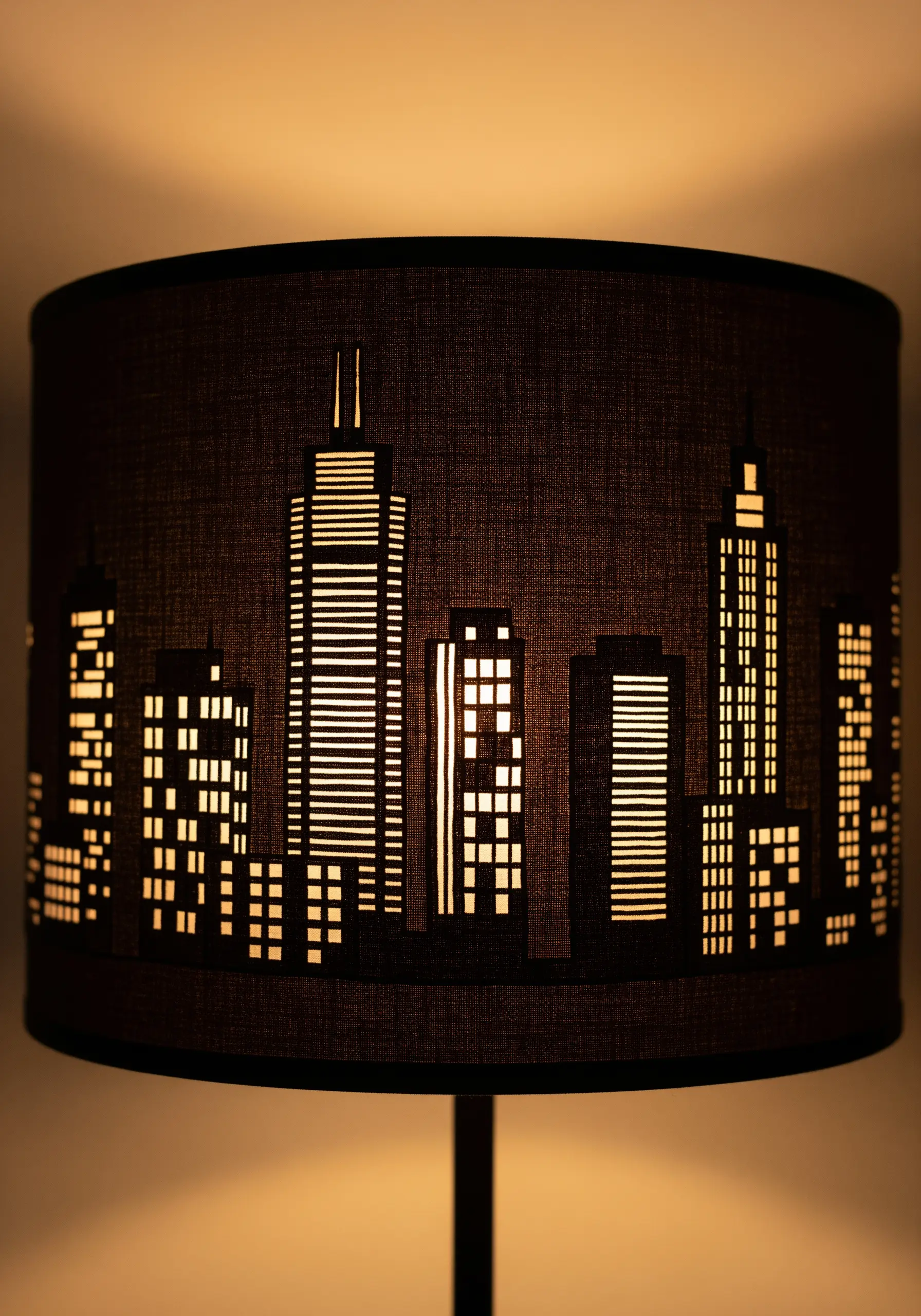 A black lampshade with a cut-out cityscape design that glows when the light is on.