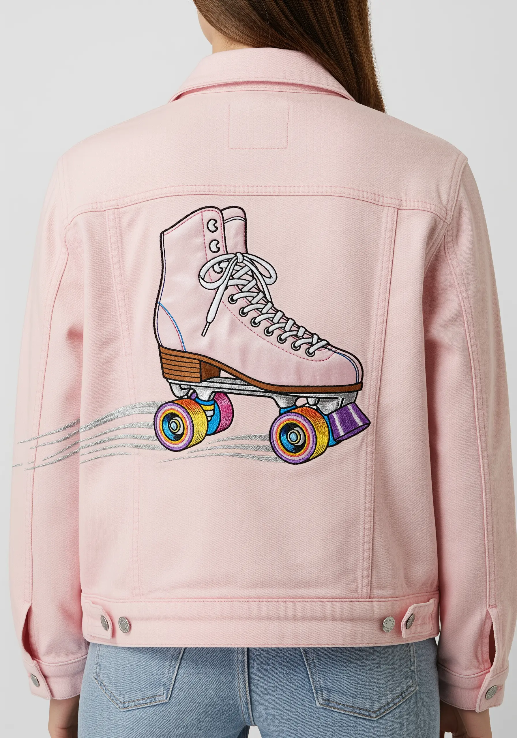 A pink roller skate with rainbow wheels embroidered on the back of a pink denim jacket.