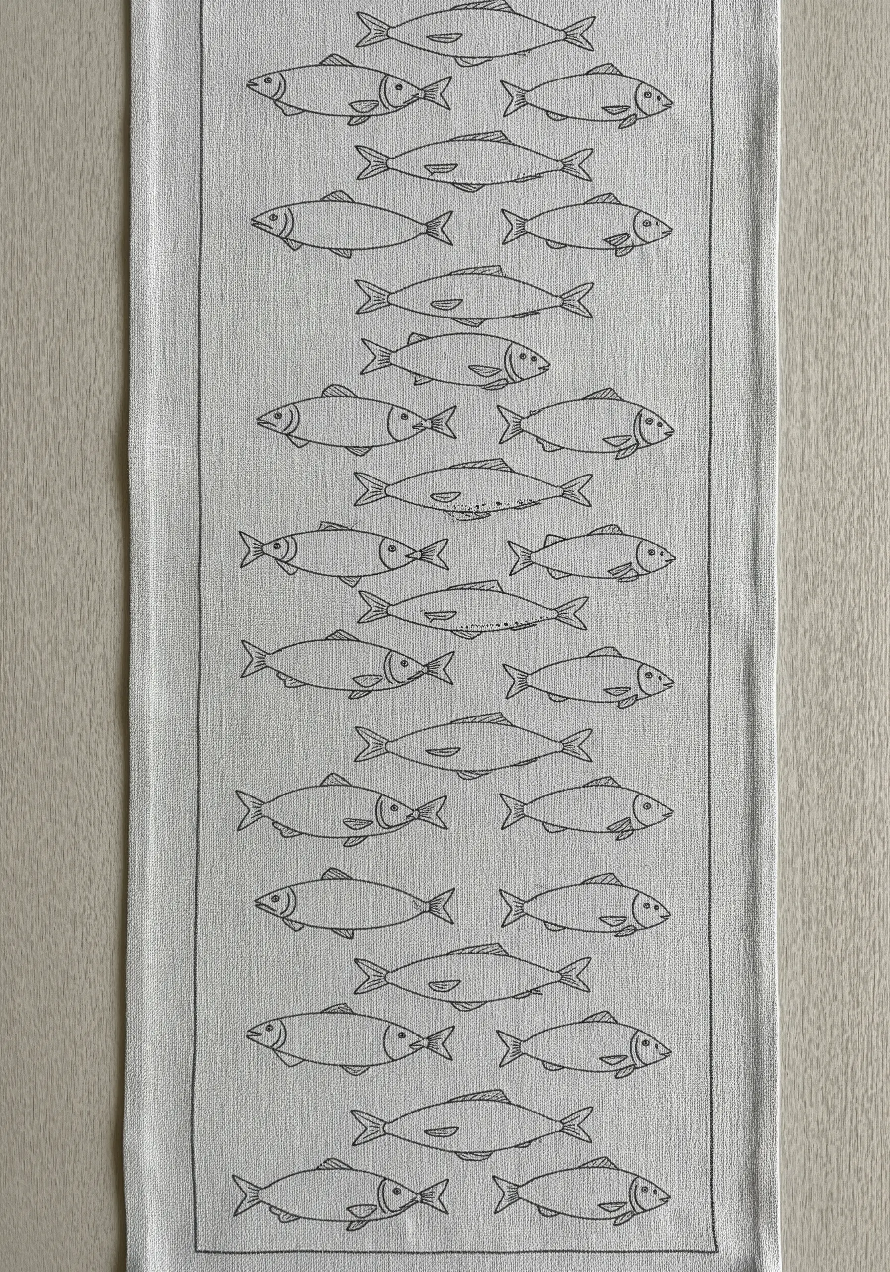 A pattern of line-art fish swimming in alternating directions on a long table runner.
