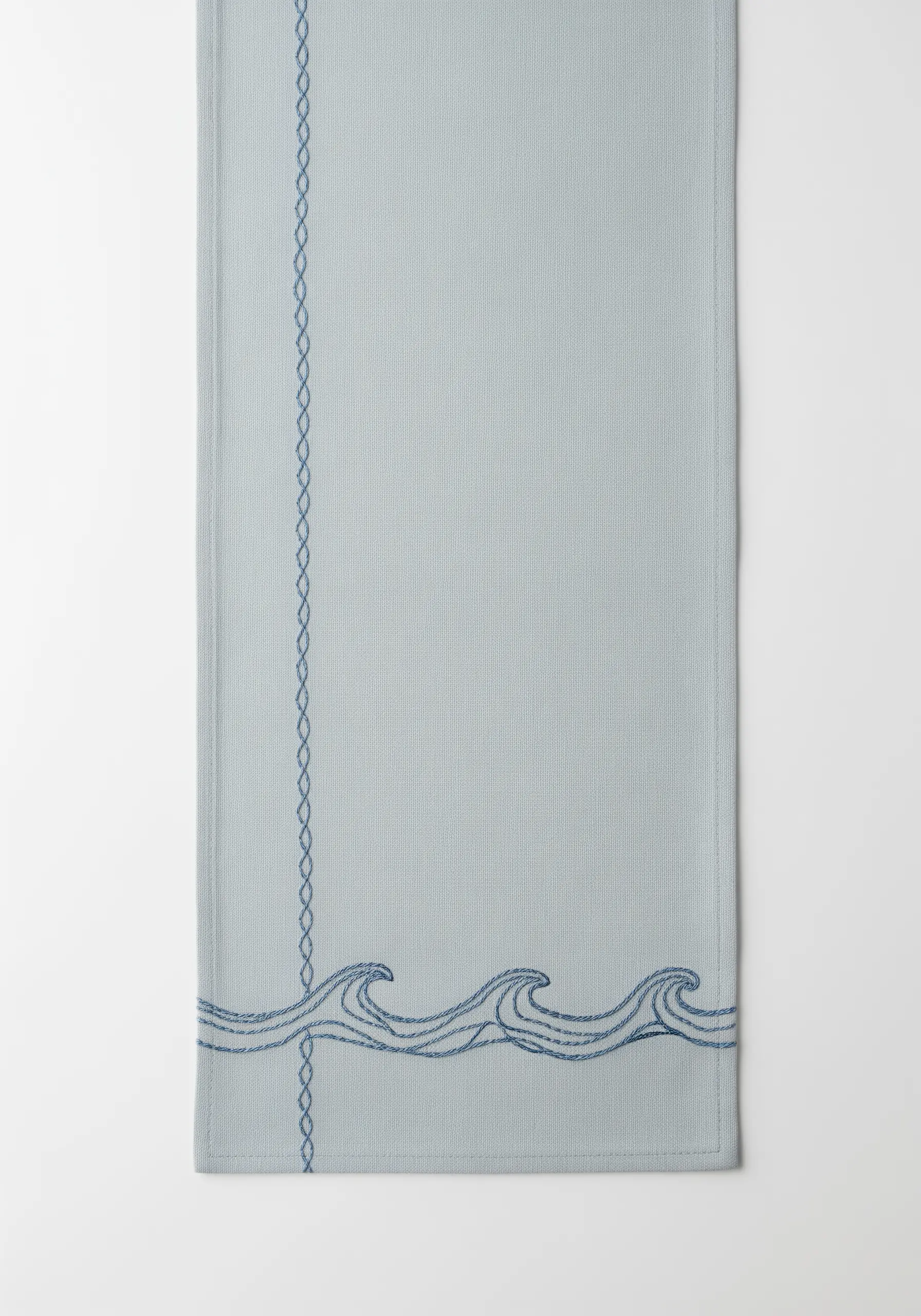 Embroidered ocean wave and line motifs in blue thread on light blue fabric.