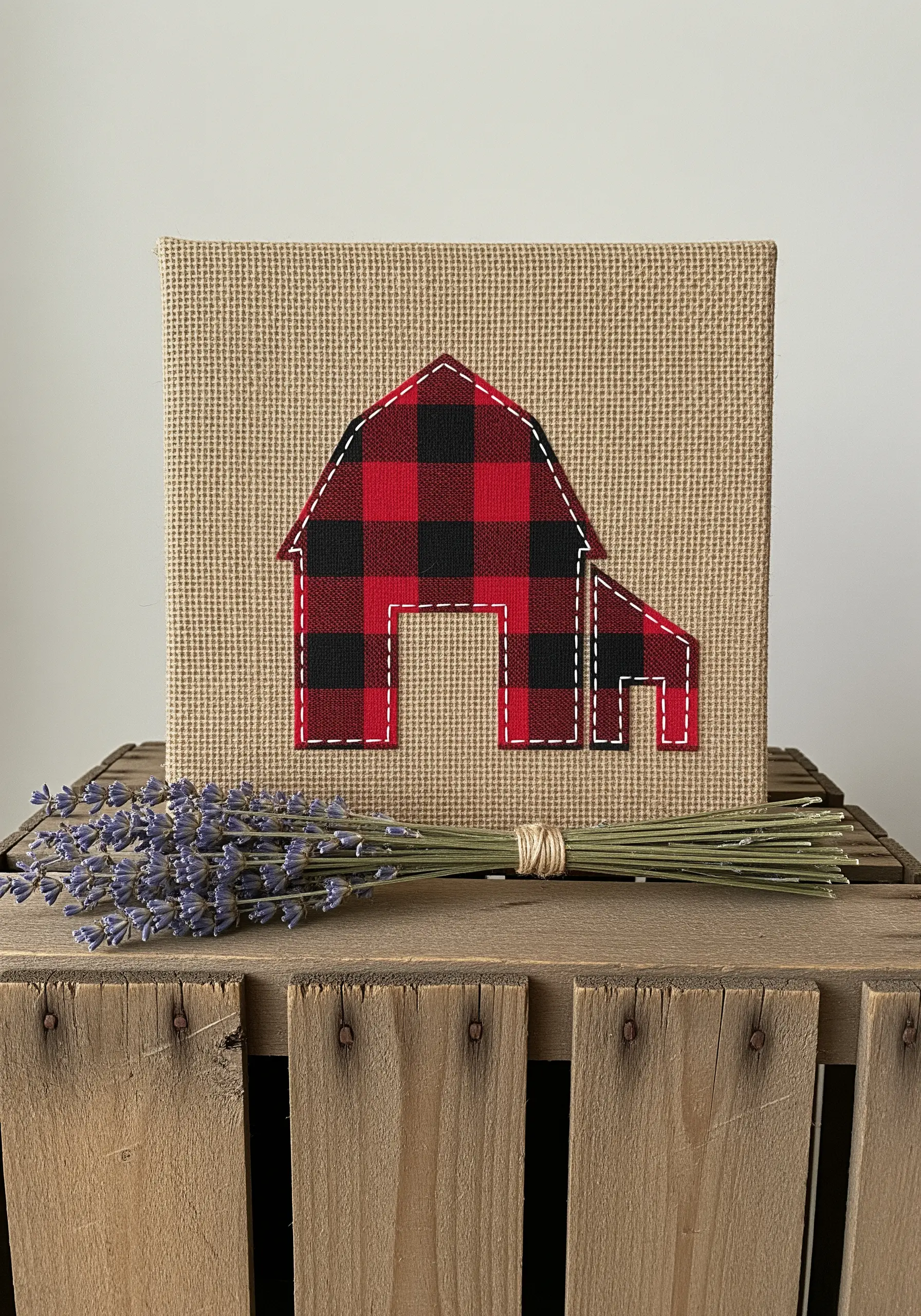 A red and black buffalo check fabric barn appliquéd onto a rustic burlap canvas.