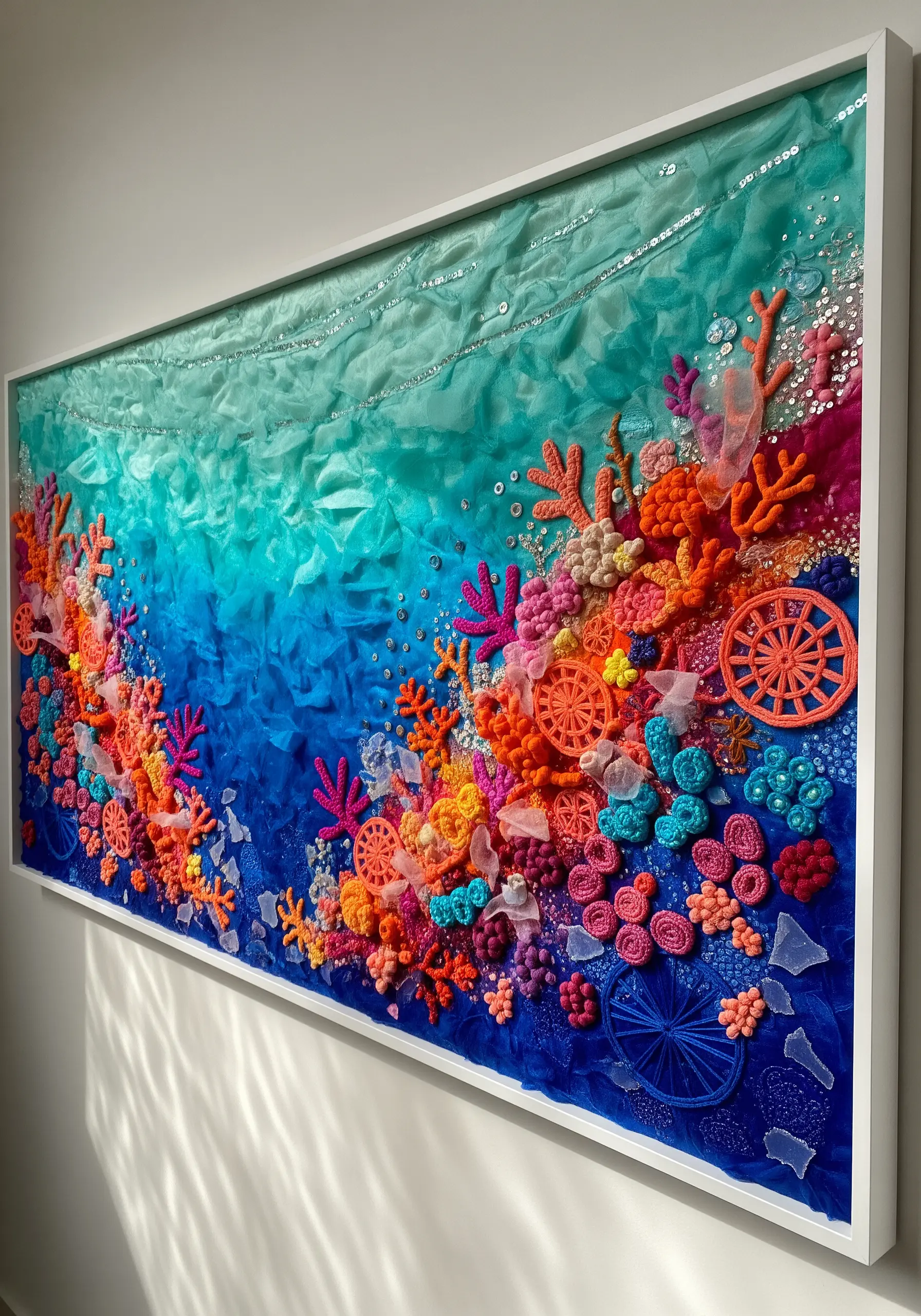 A large, vibrant fiber art collage depicting a coral reef with crochet, beads, and tulle.