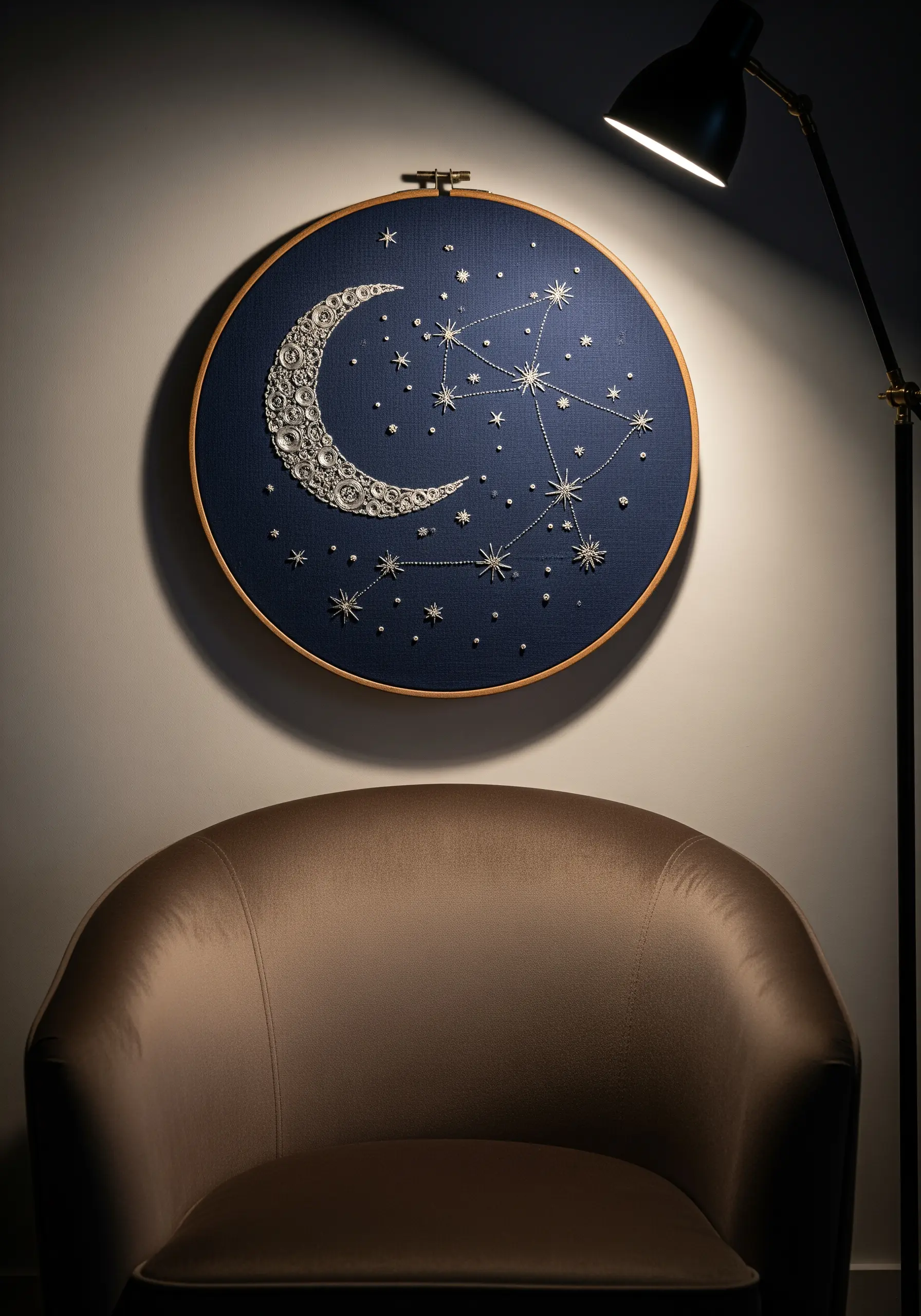 A textured crescent moon and constellations embroidered on dark navy fabric in a large hoop.