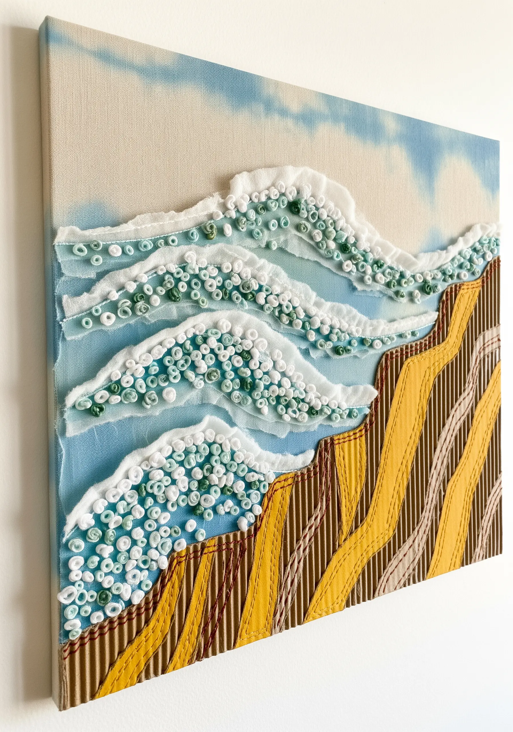 Mixed-media seascape using fabric quilling for waves and corrugated cardboard for cliffs.