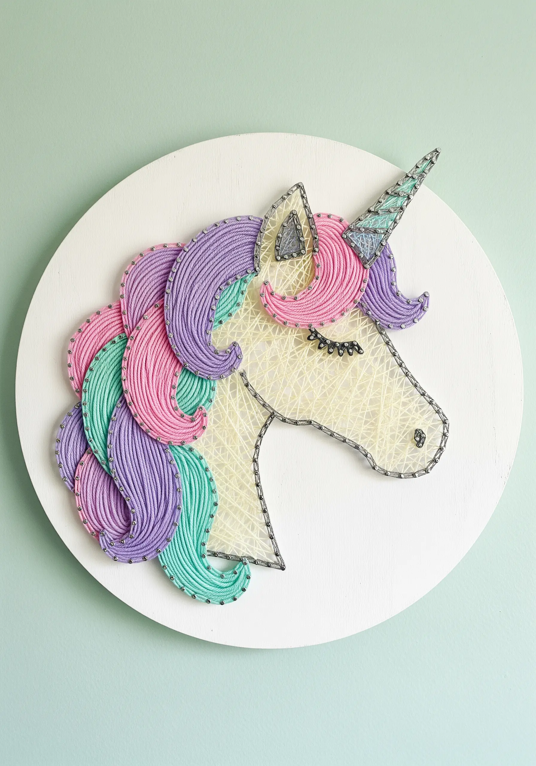 Embroidery detail of a unicorn mane with flowing, multi-colored satin stitches.