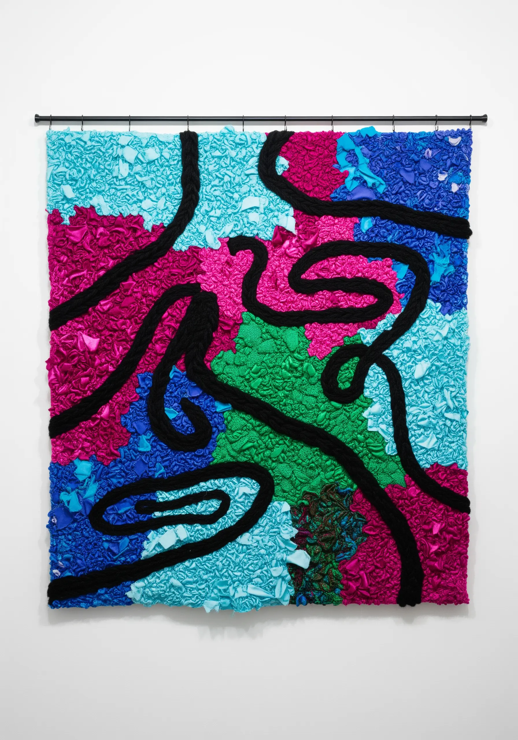 Abstract wall art with highly textured, scrunched fabric in bright colors and a thick black line.