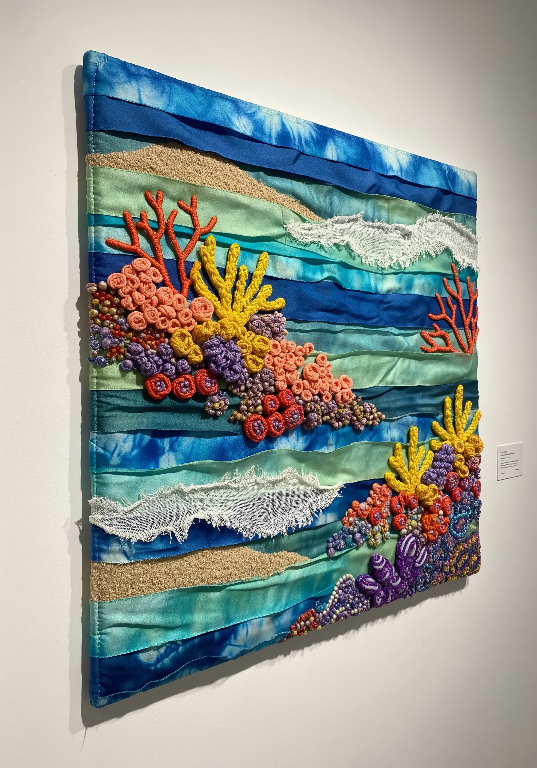 Embroidered coral reef with French knots on a collage of blue and green ribbons.
