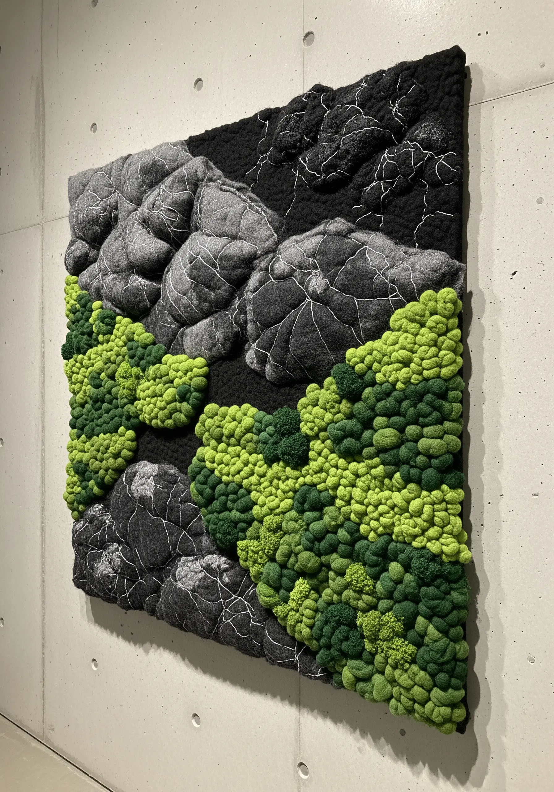 3D textile art with padded gray fabric for rocks and dense green French knots for moss.
