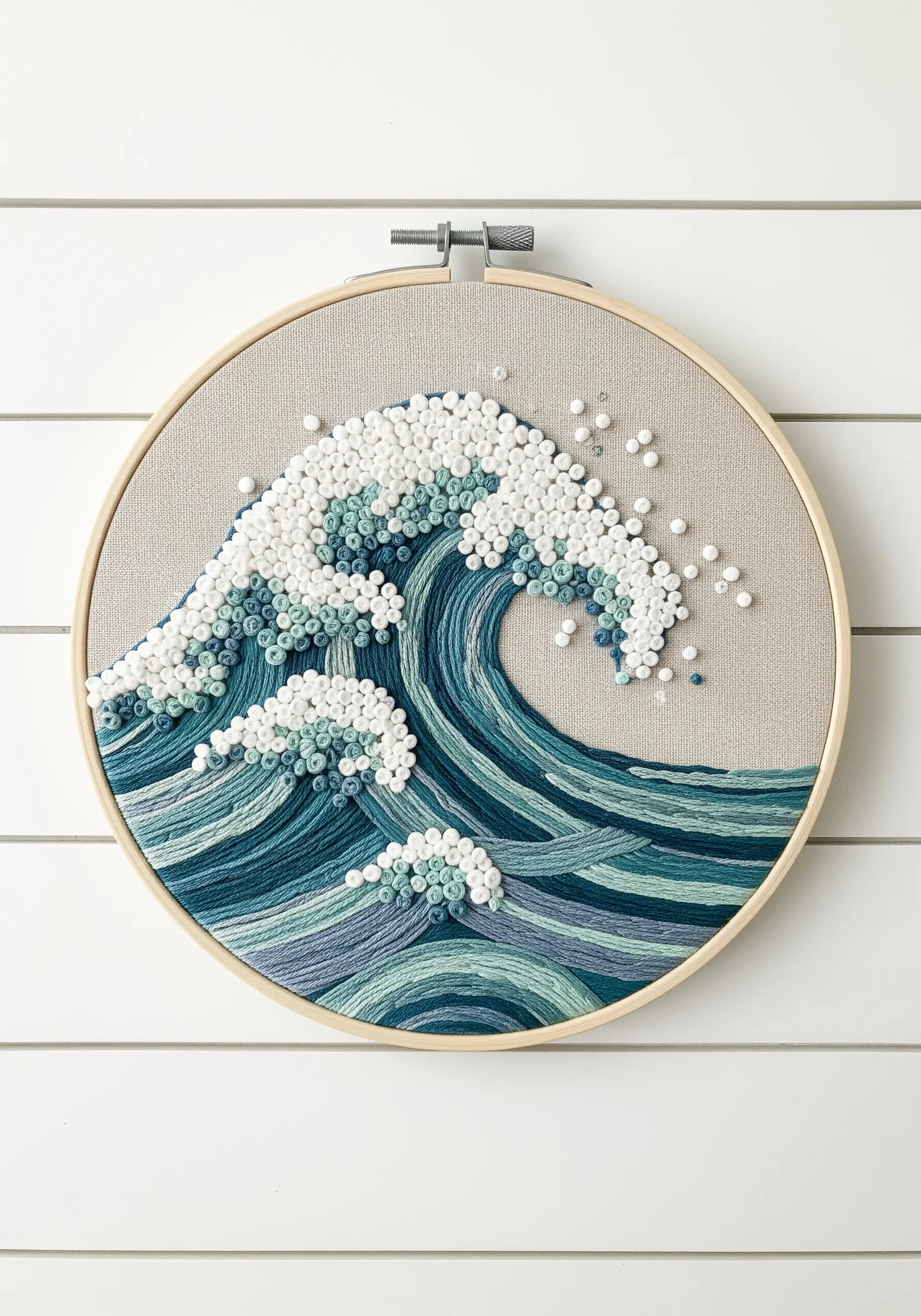 Embroidery of a large ocean wave with French knot seafoam and thread-painted water.
