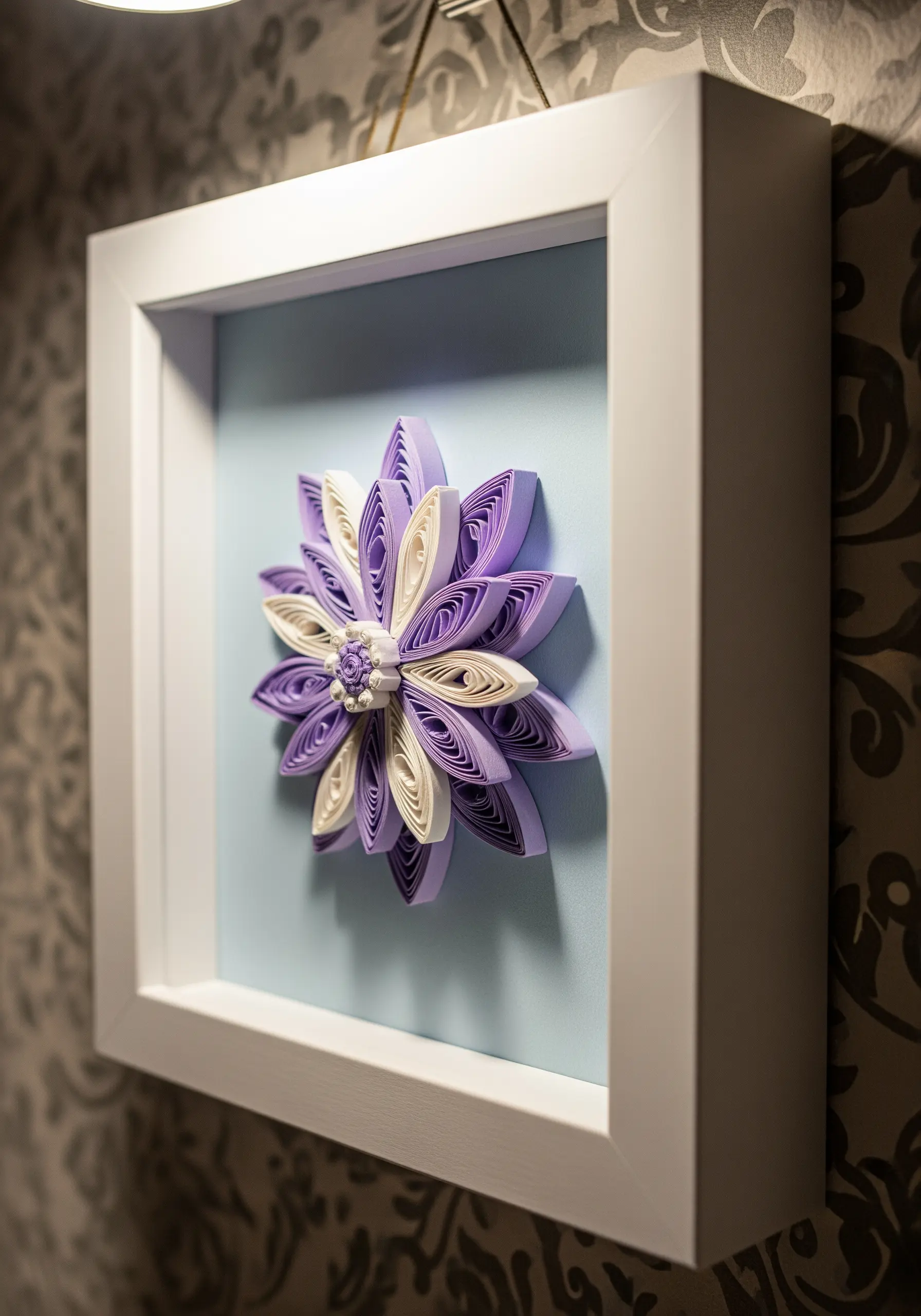 A 3D paper quilling flower in shades of purple and white, mounted in a deep white frame.