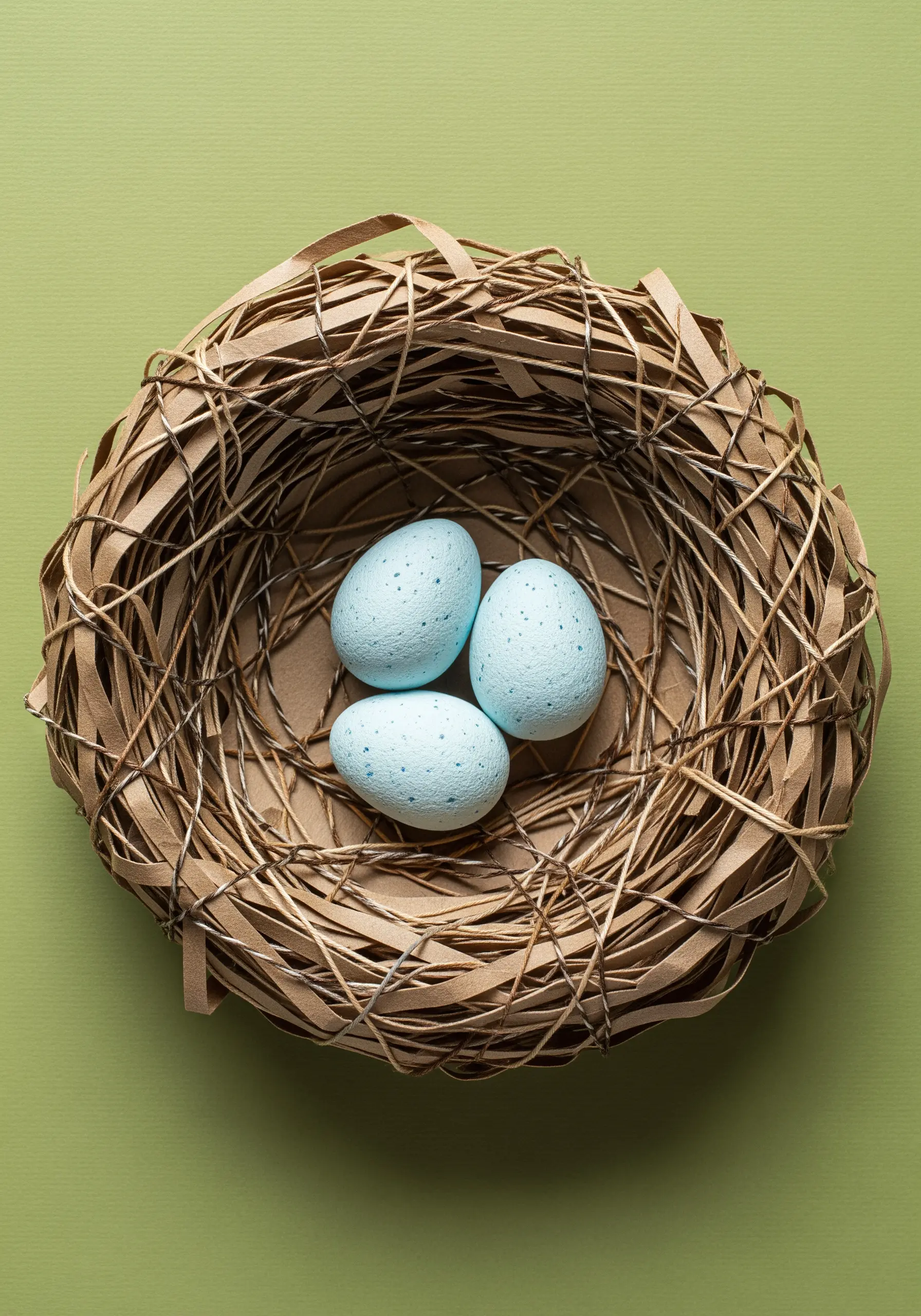 A bird's nest sculpted from thin strips of brown paper held together with thread.