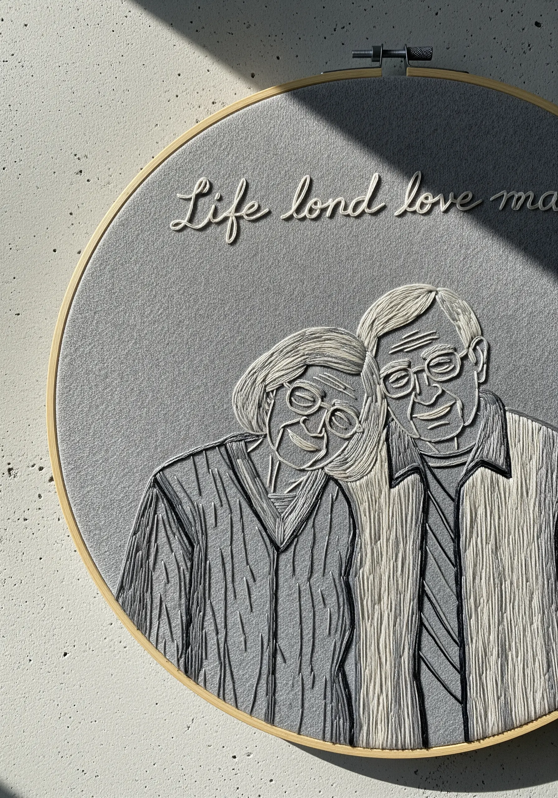 An elderly couple's portrait filled with directional satin stitches in shades of grey and white.