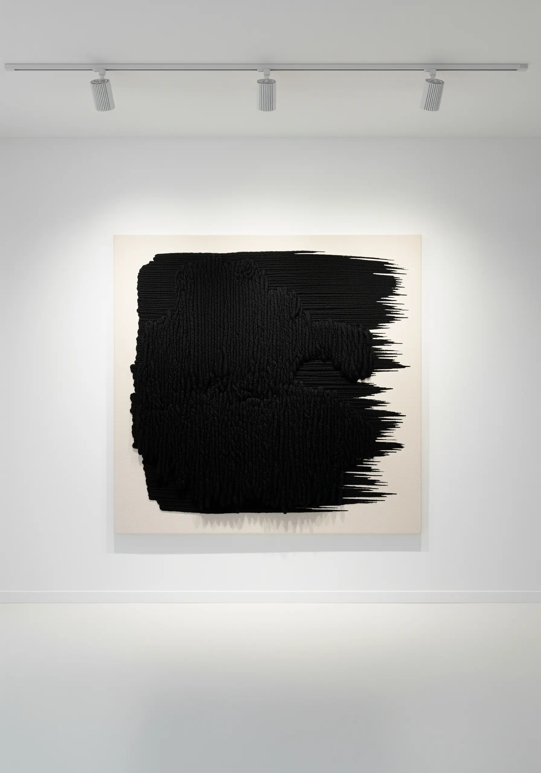A large abstract black shape with intense horizontal texture on a white canvas.