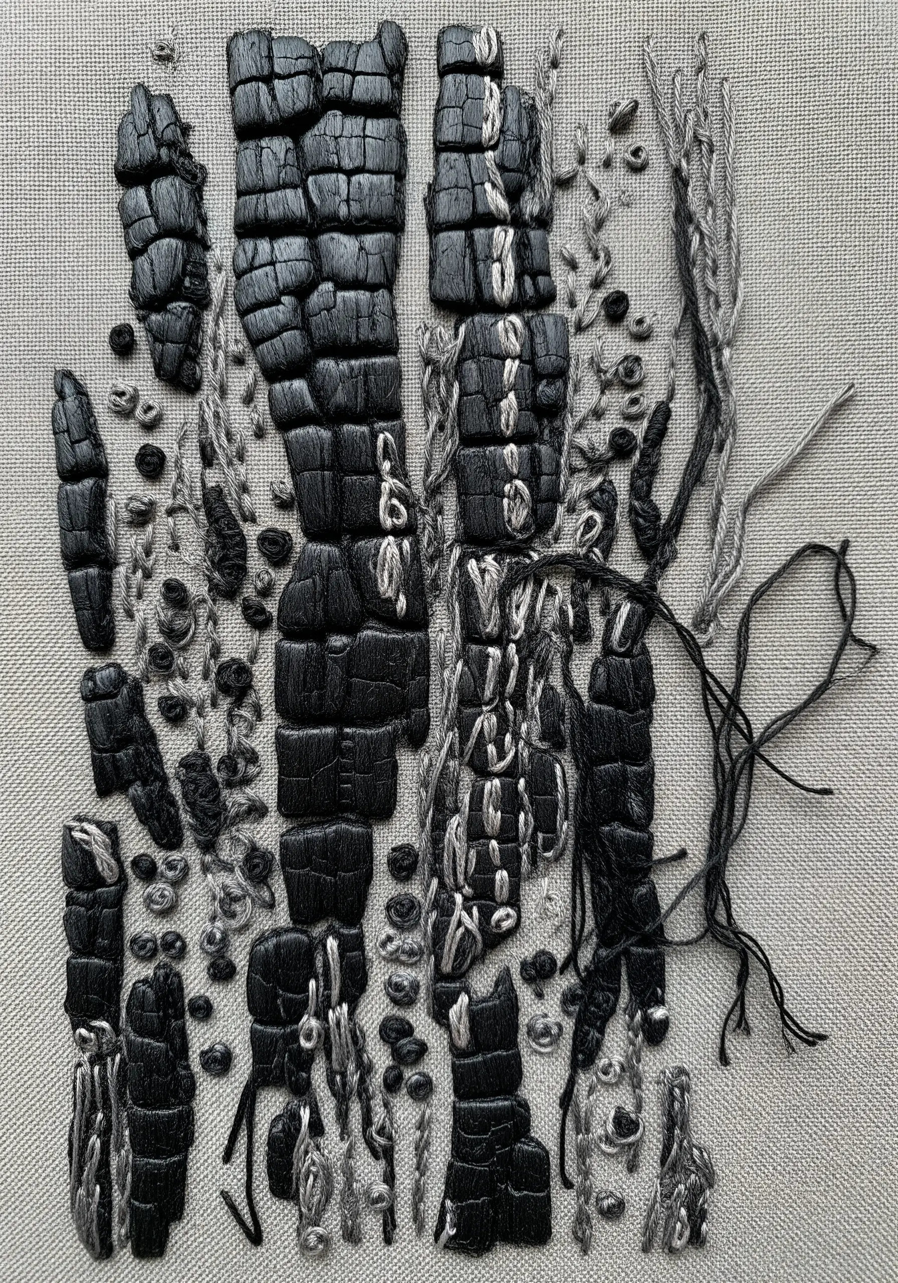 Highly textural embroidery of charred wood, using padded satin stitch and loose thread work.