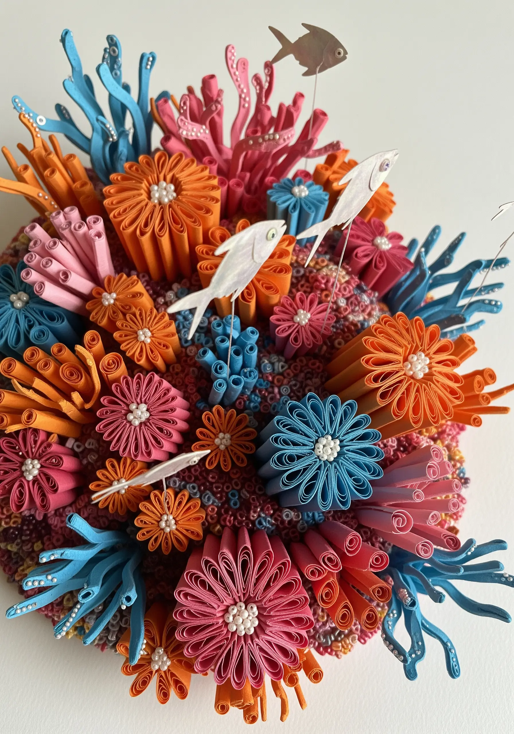 A vibrant, 3D coral reef sculpture made with paper quilling and beads, inspiring stumpwork embroidery.
