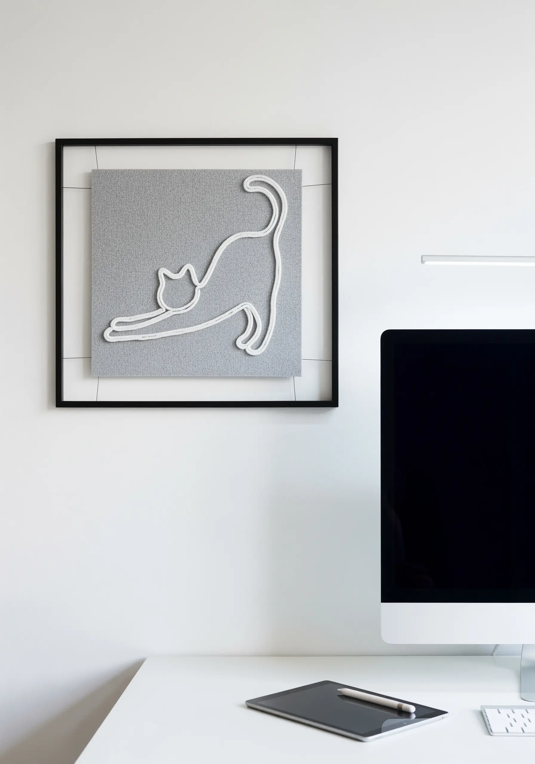 A minimalist cat outline created with thick white cord on a grey fabric panel.