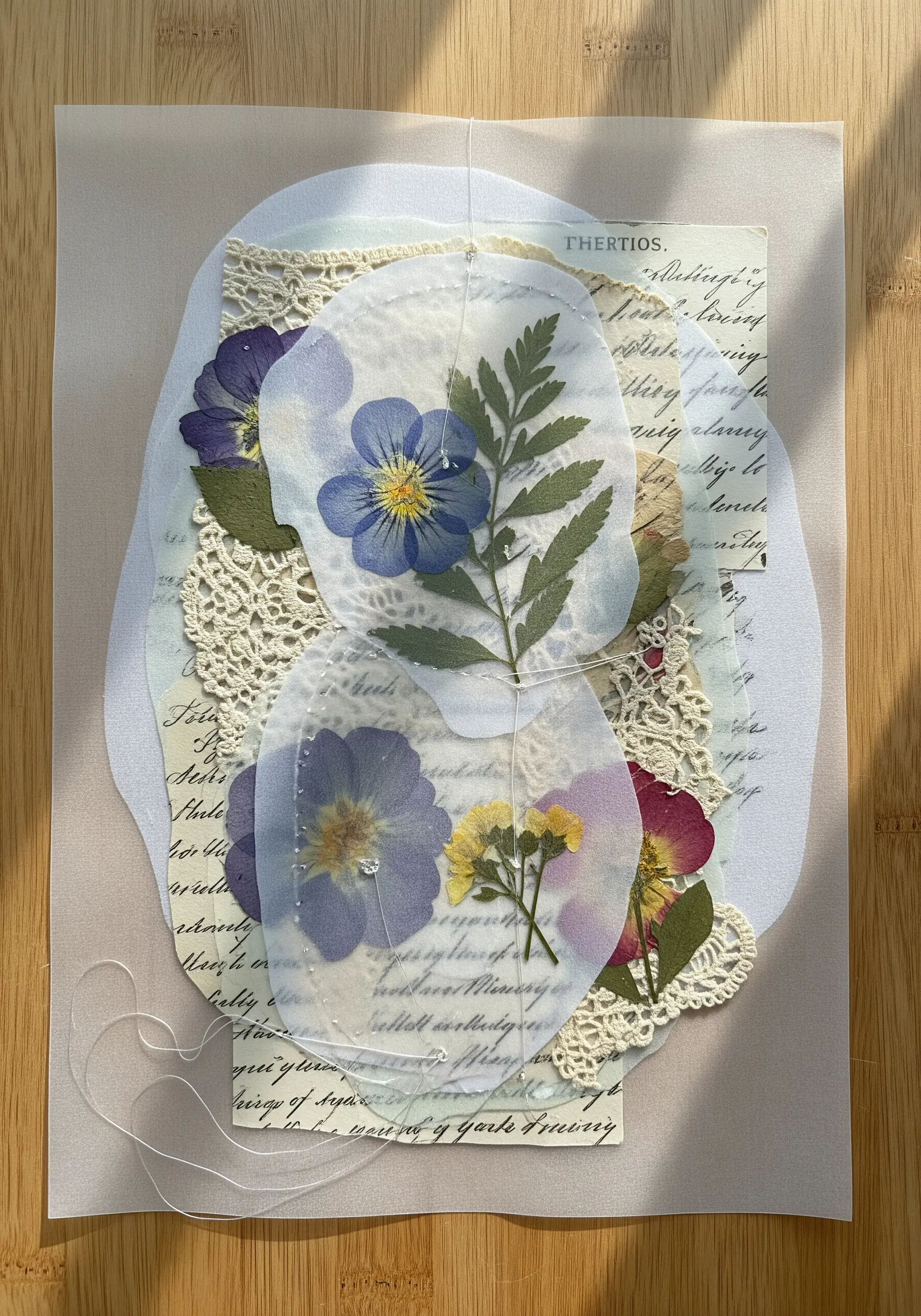 A delicate collage of pressed flowers, lace, and vellum held together with fine thread.