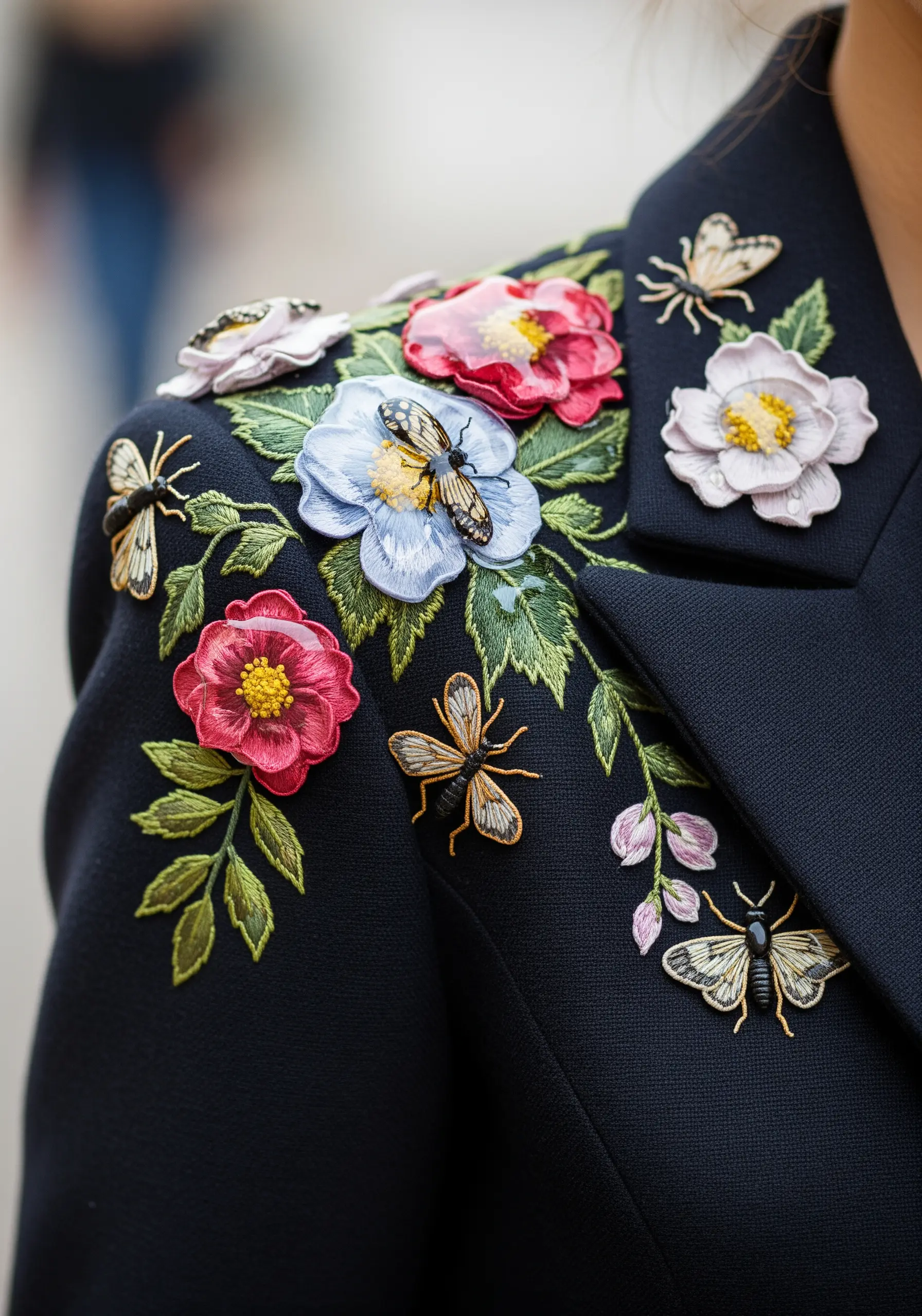 Embroidered flowers and bees on a jacket, with some petals and wings coated in glossy resin.
