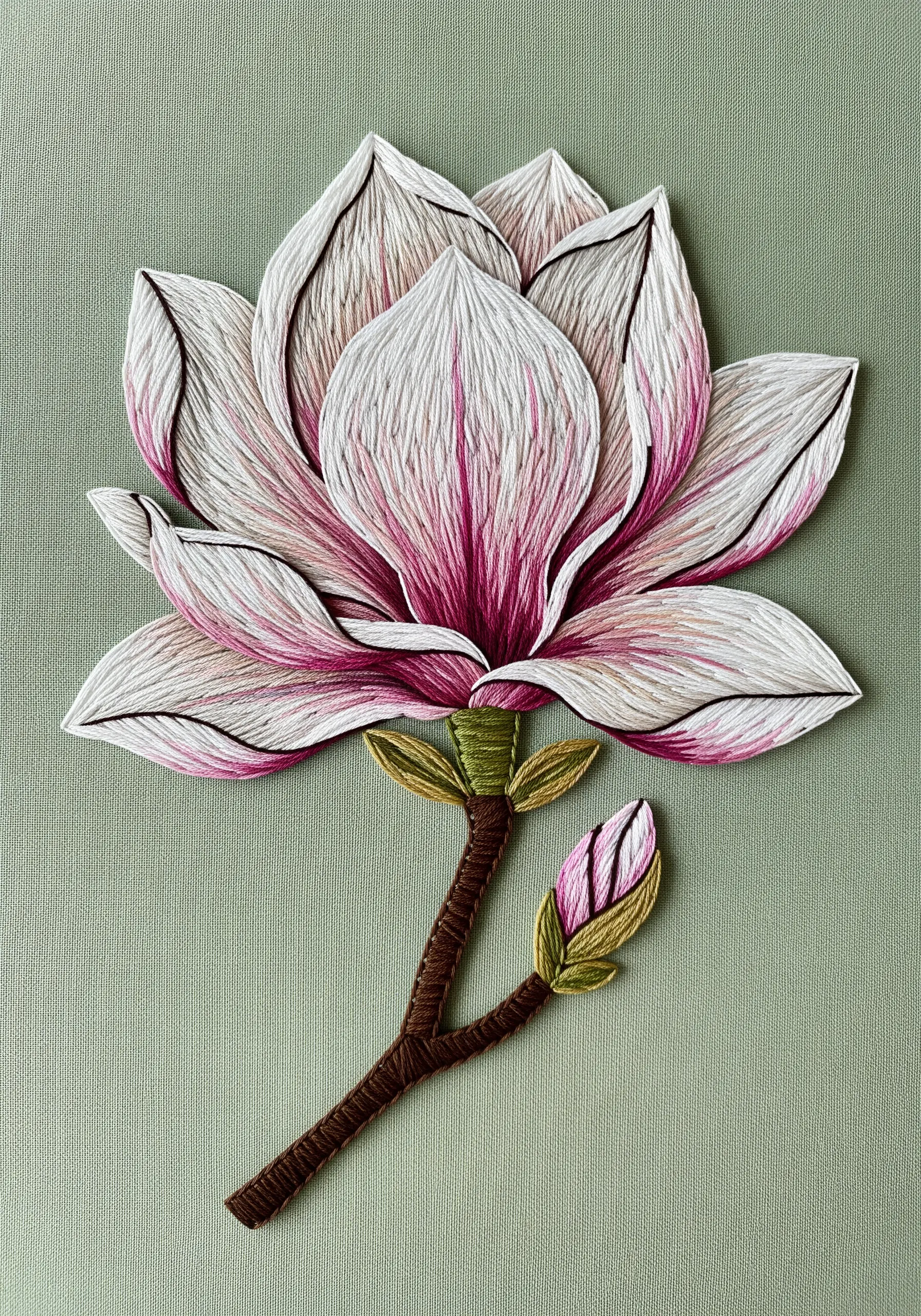 A large, realistic embroidered magnolia blossom with delicate pink and white shading.