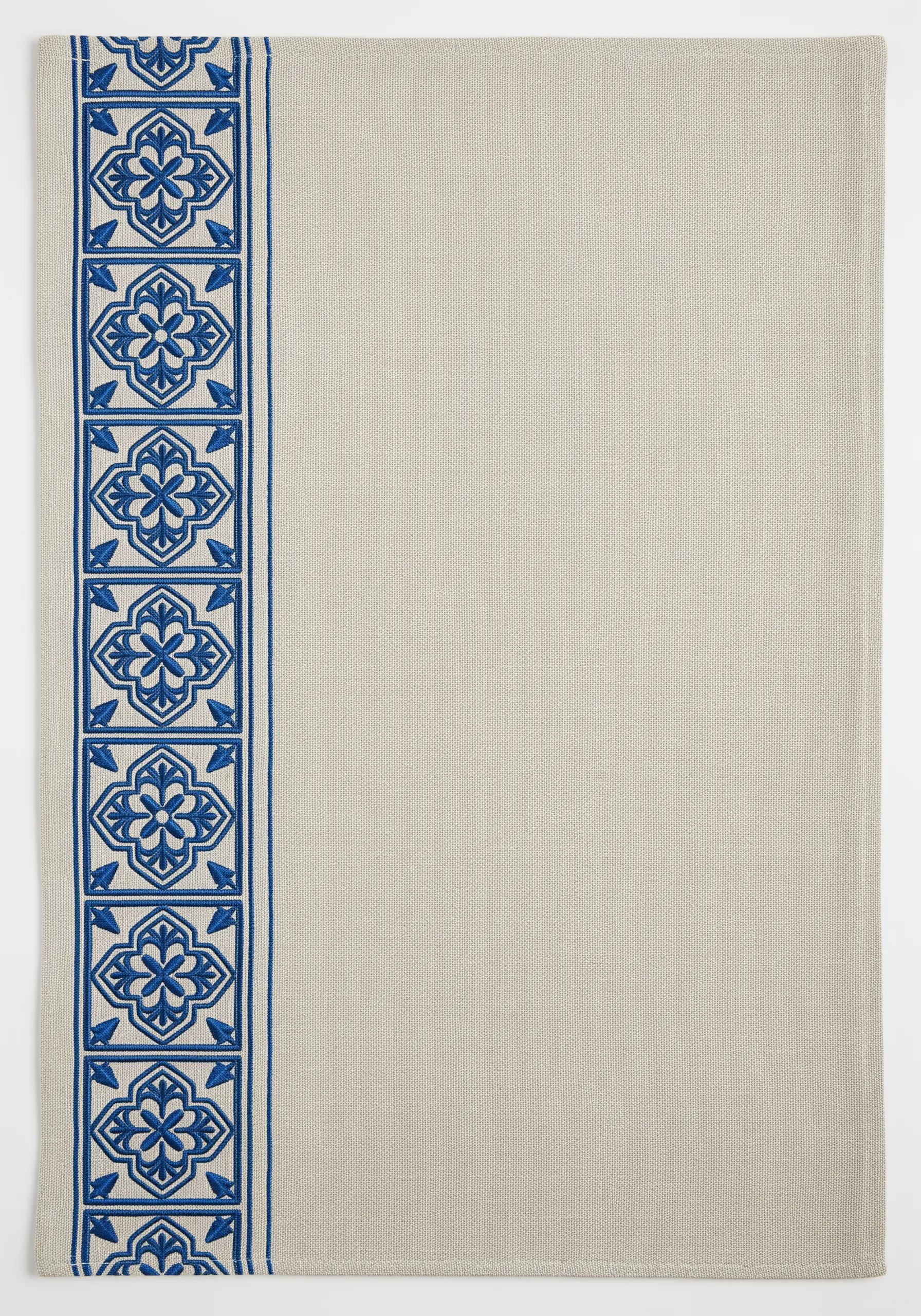 A table runner border of embroidered blue tiles, using both outlines and filled shapes.
