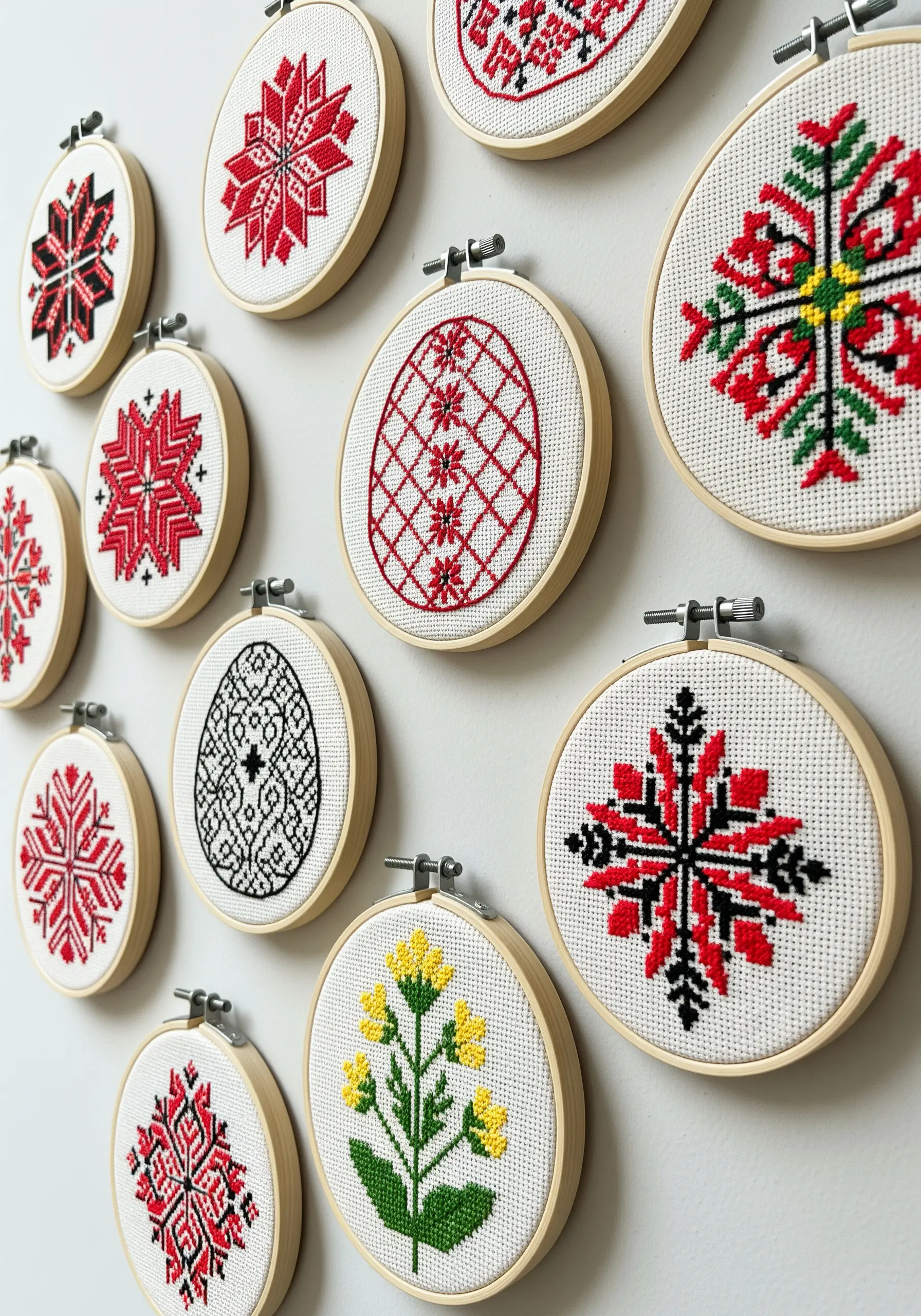 A gallery wall of small embroidery hoops featuring Slavic red-and-black cross-stitch motifs.