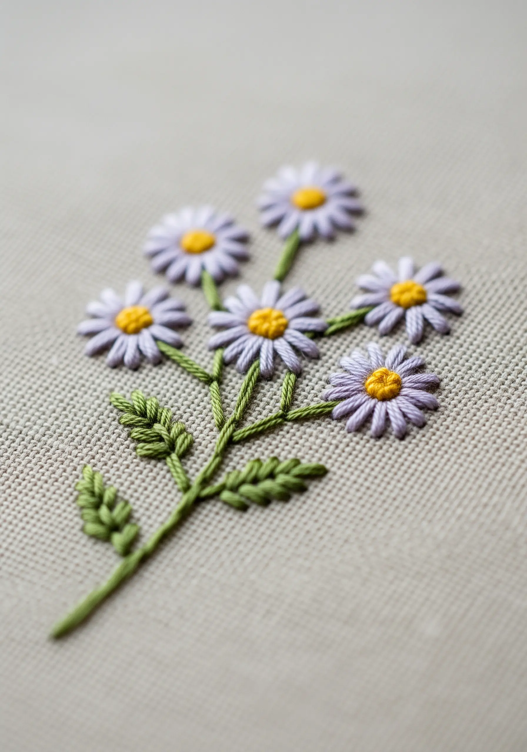 A close-up of a bouquet of purple daisies made with lazy daisy stitches and yellow French knot centers.