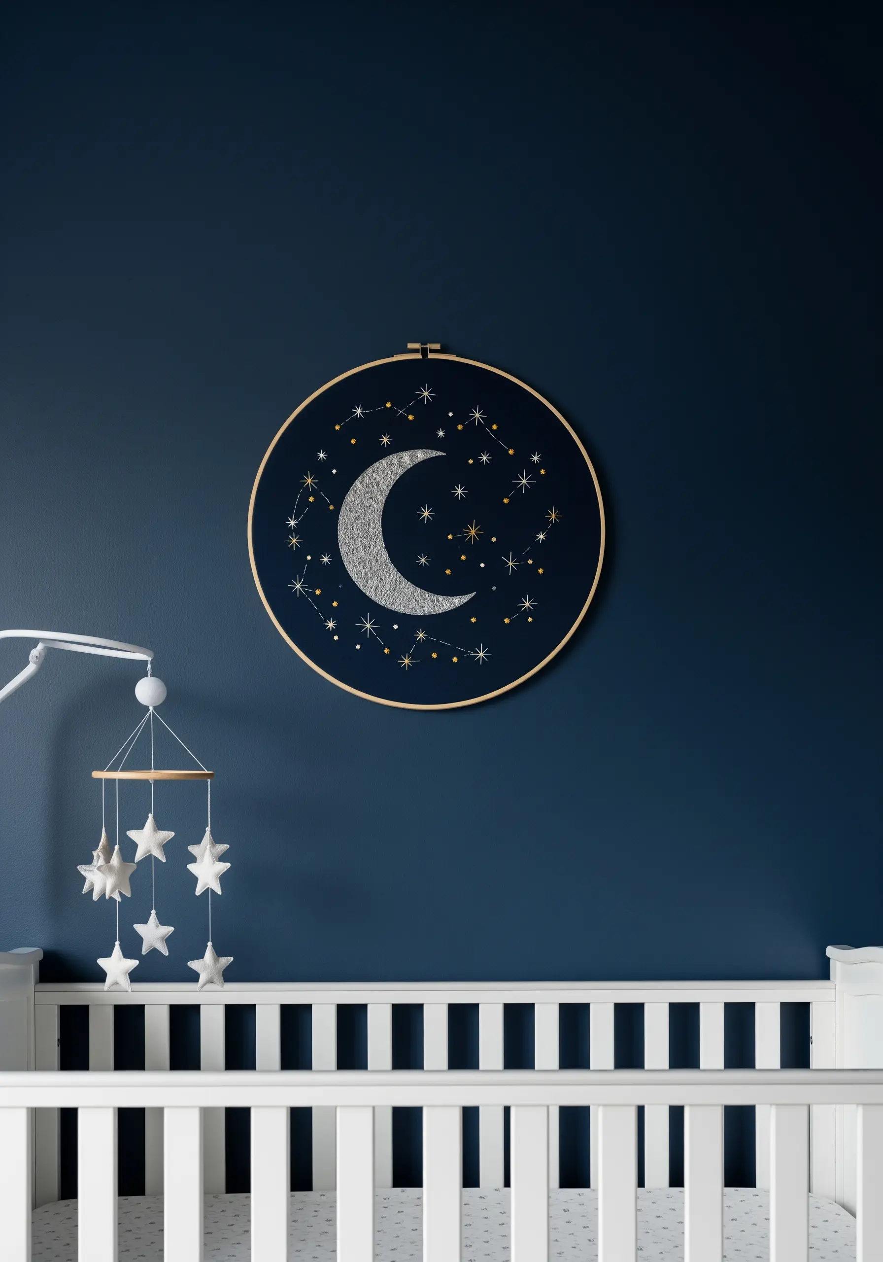 Embroidered moon and constellations using silver thread on dark blue fabric.