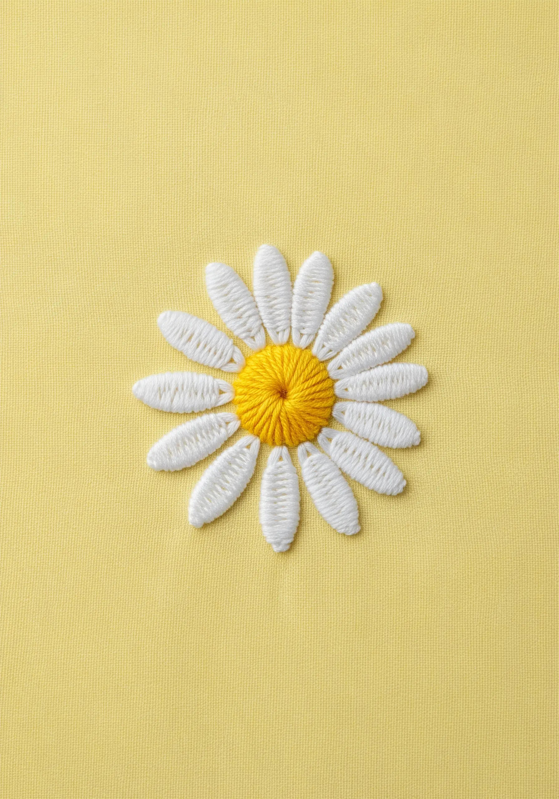 A simple embroidered daisy with white petals and a yellow center on yellow fabric.
