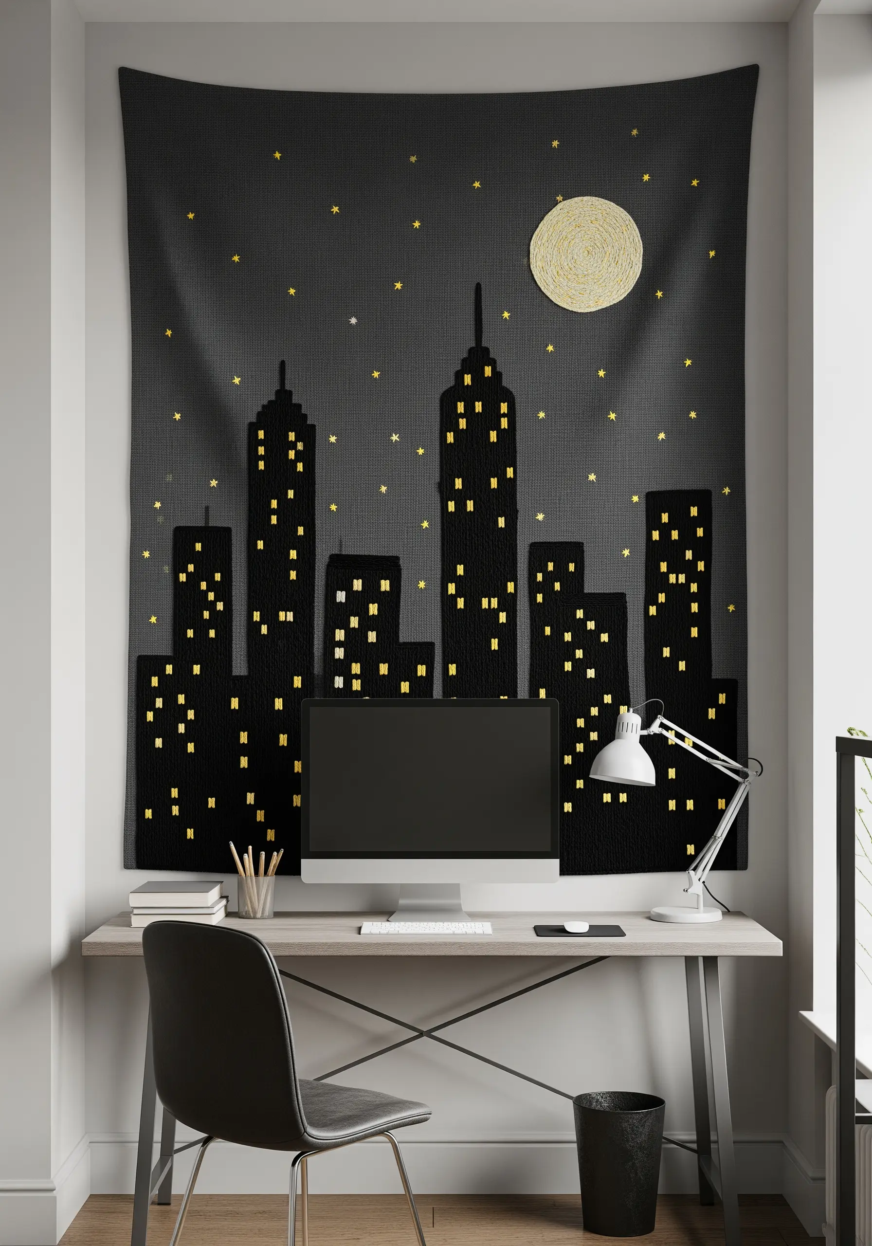 An embroidered tapestry of a city skyline at night with a full moon, hung above a desk.