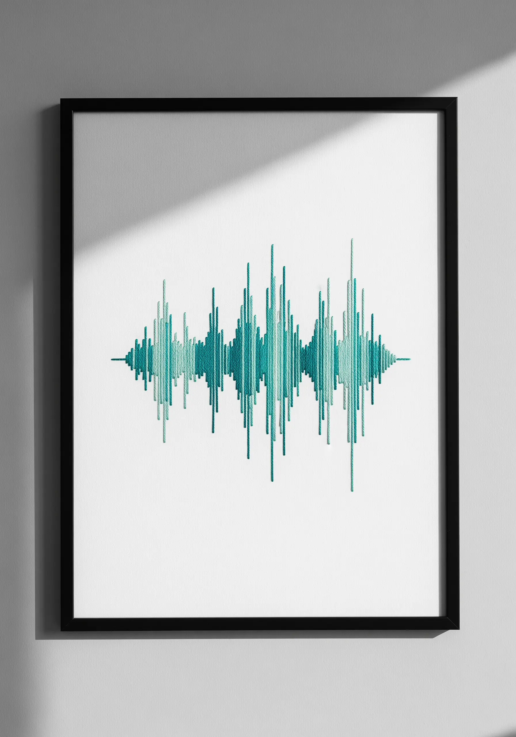 Framed embroidery of a sound wave stitched in shades of teal.