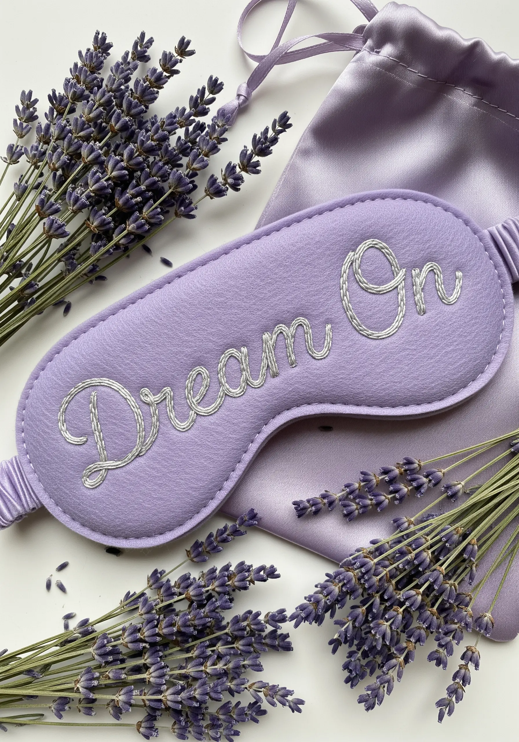 A lavender felt sleep mask with 'Dream On' embroidered in silver metallic thread.