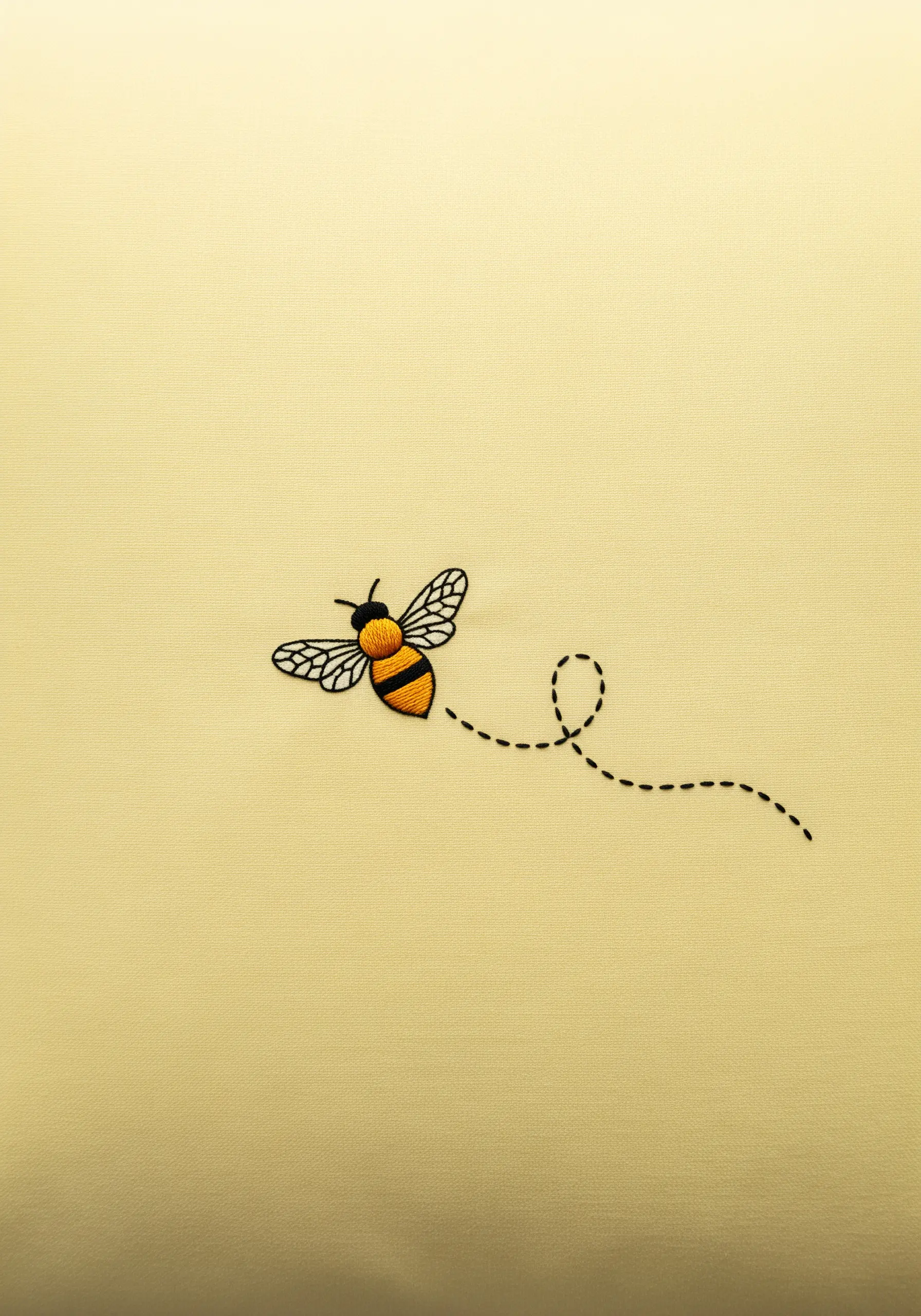 A small embroidered bee with a dotted flight path on a pale yellow pillowcase.