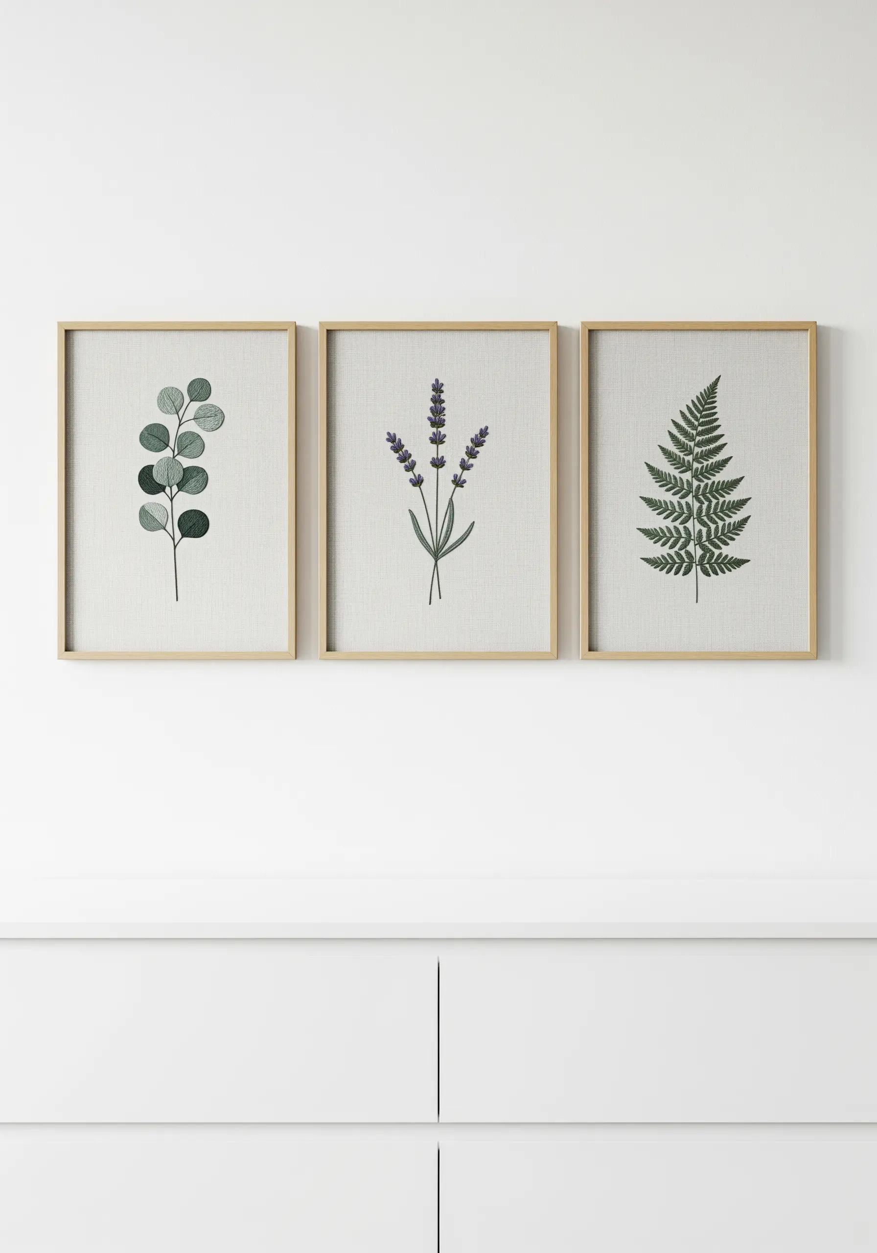 Three framed embroidery pieces showing minimalist eucalyptus, lavender, and fern botanicals.