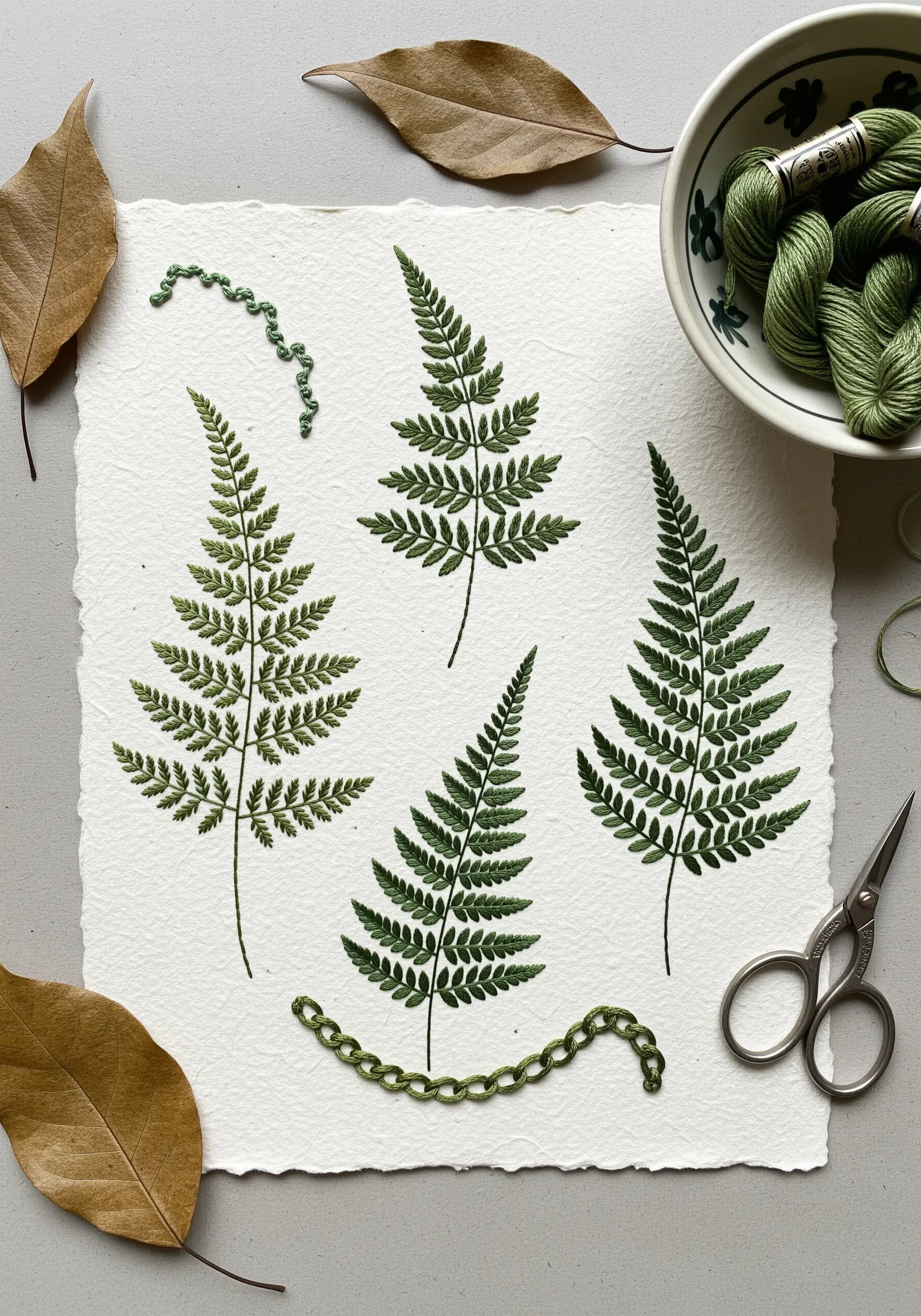 Delicate green fern leaves embroidered on thick, textured watercolor paper.