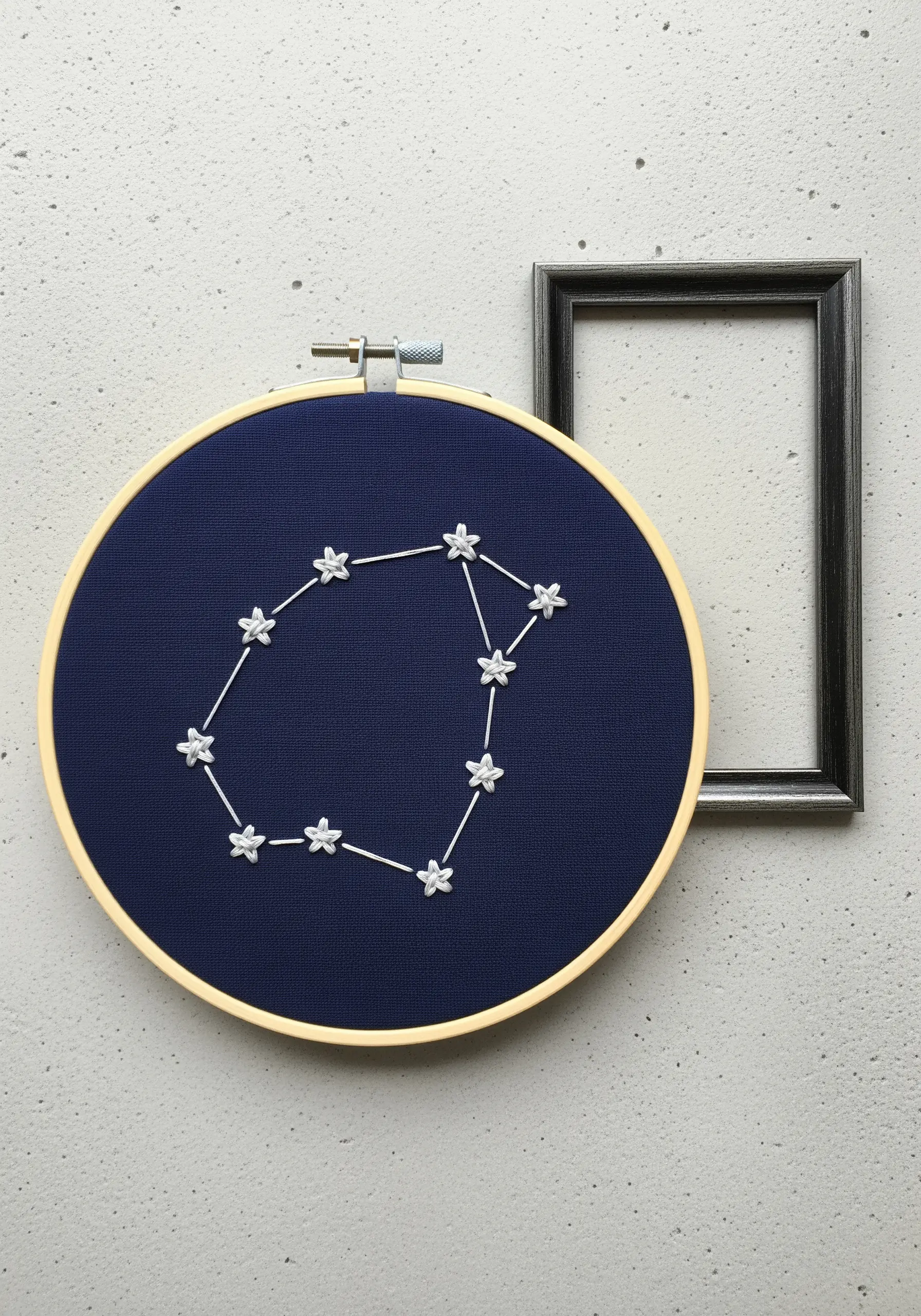 A constellation embroidered with white lazy-daisy stars on a navy blue background.