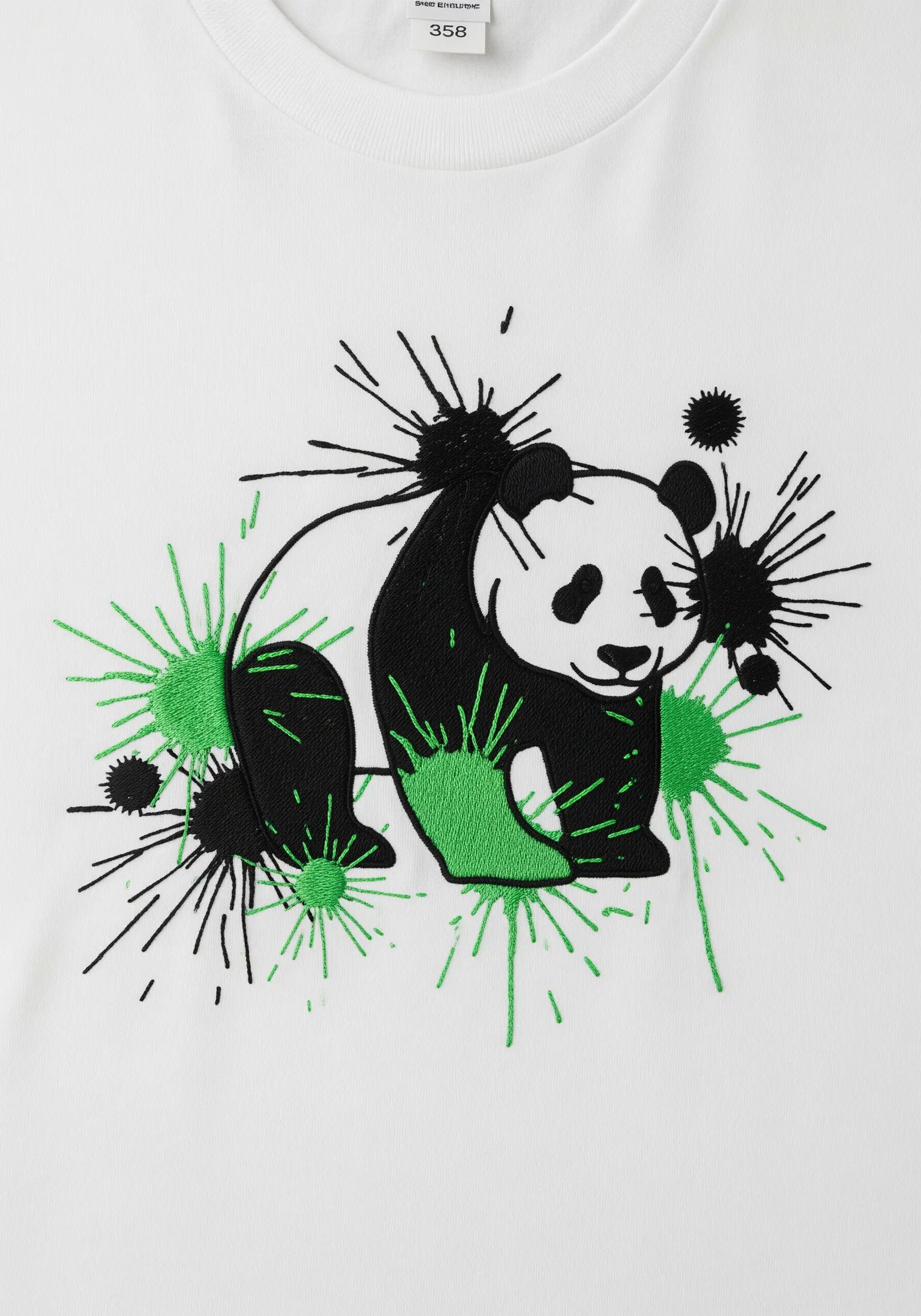 A panda embroidered on a white shirt, surrounded by dynamic green and black thread splatters.