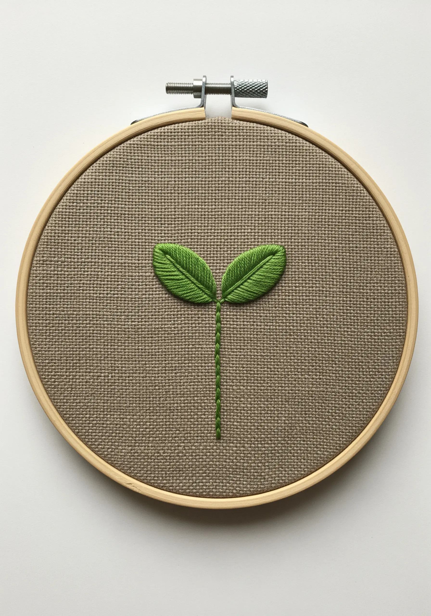 A small green sprout with two leaves made with fishbone stitch.