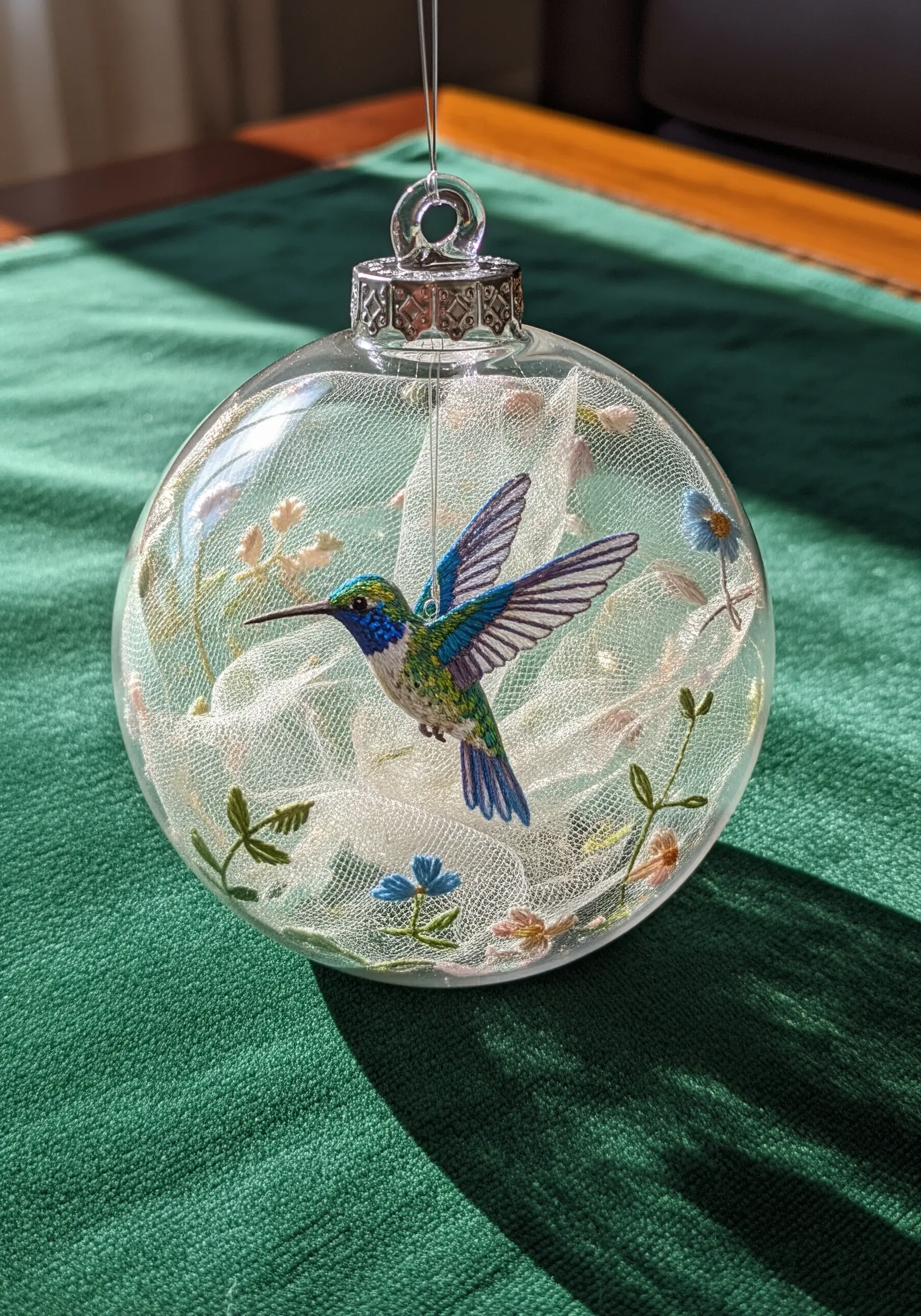 Hummingbird embroidery inside a clear glass ornament bulb